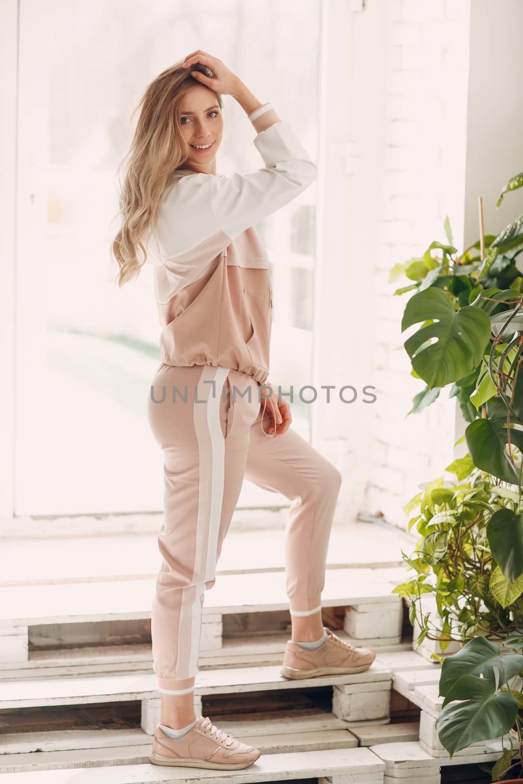 Young athletic girl smiling in tracksuit in full growth by primipil