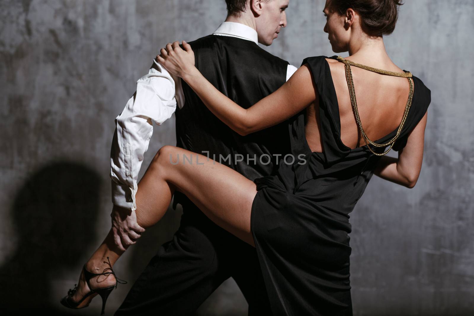 Young pretty woman in black dress and man dance tango