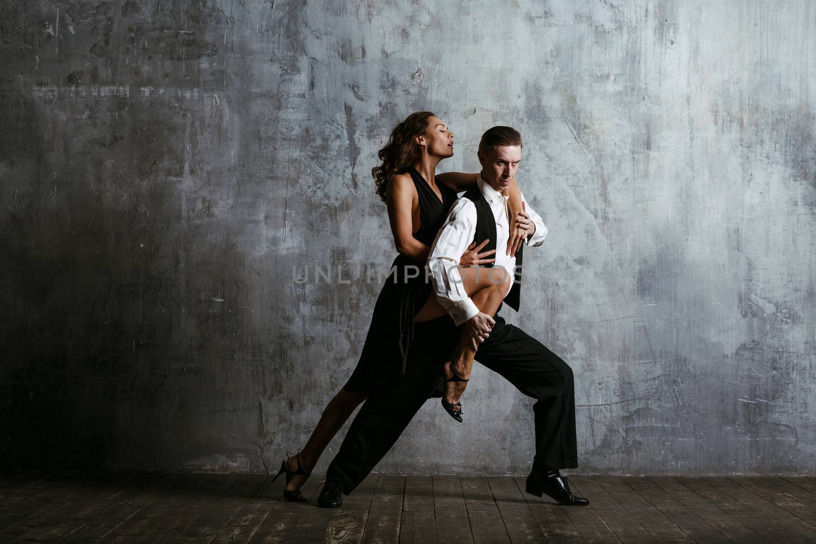 Young pretty woman in black dress and man dance tango