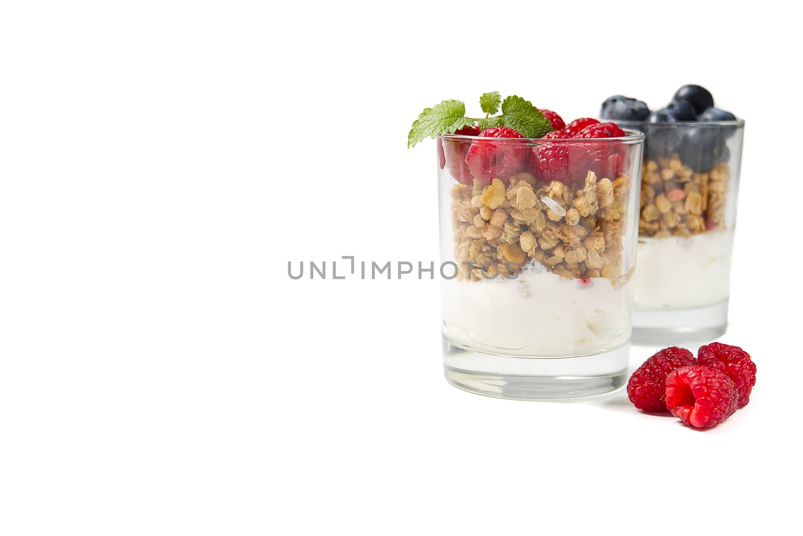 muesli dessert with yogurt and blueberry in a glass over white background. Granola in glass with berries and yogurt. by PhotoTime