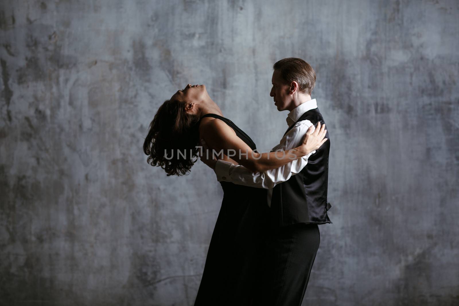 Young pretty woman in black dress and man dance tango by primipil