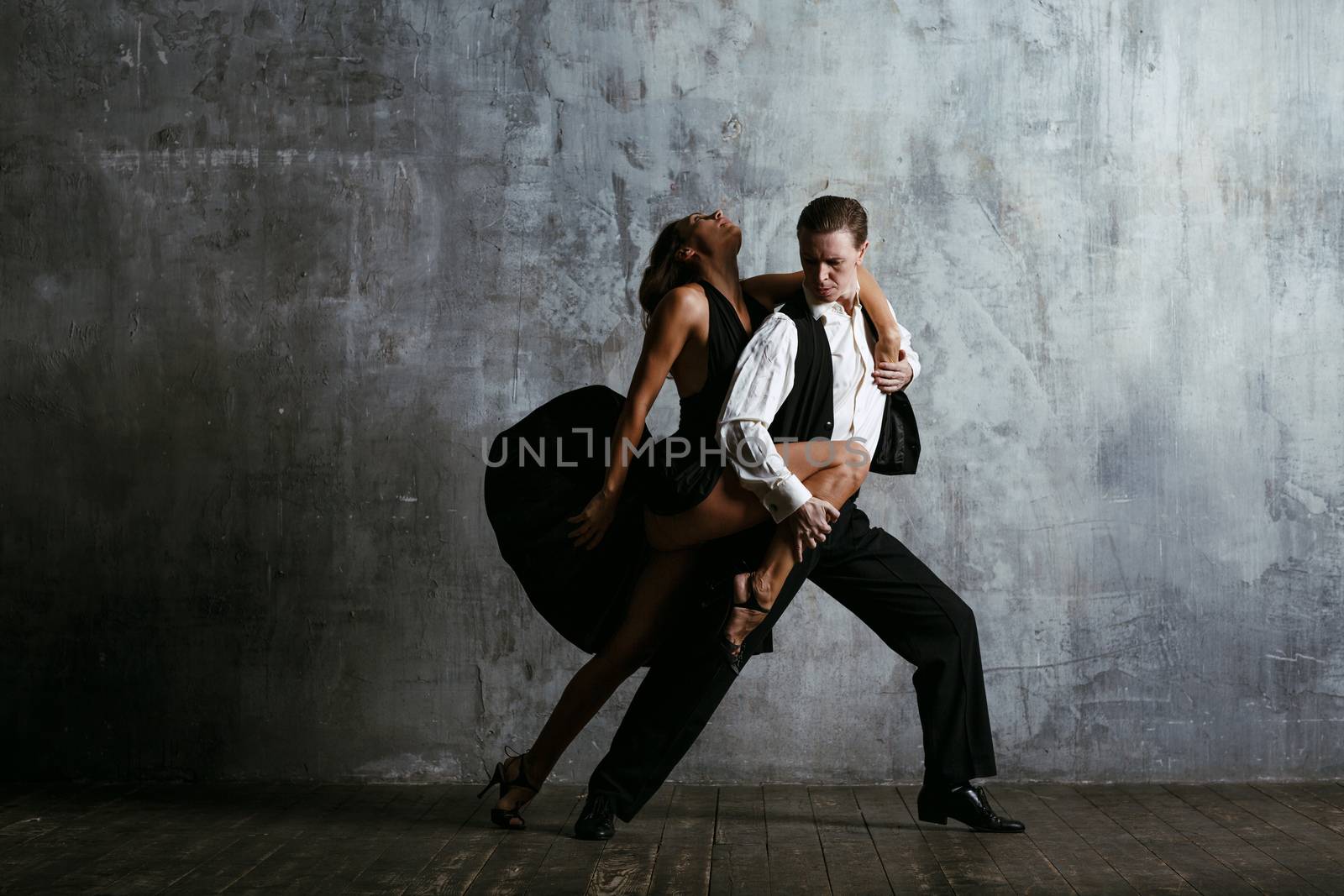 Young pretty woman in black dress and man dance tango by primipil