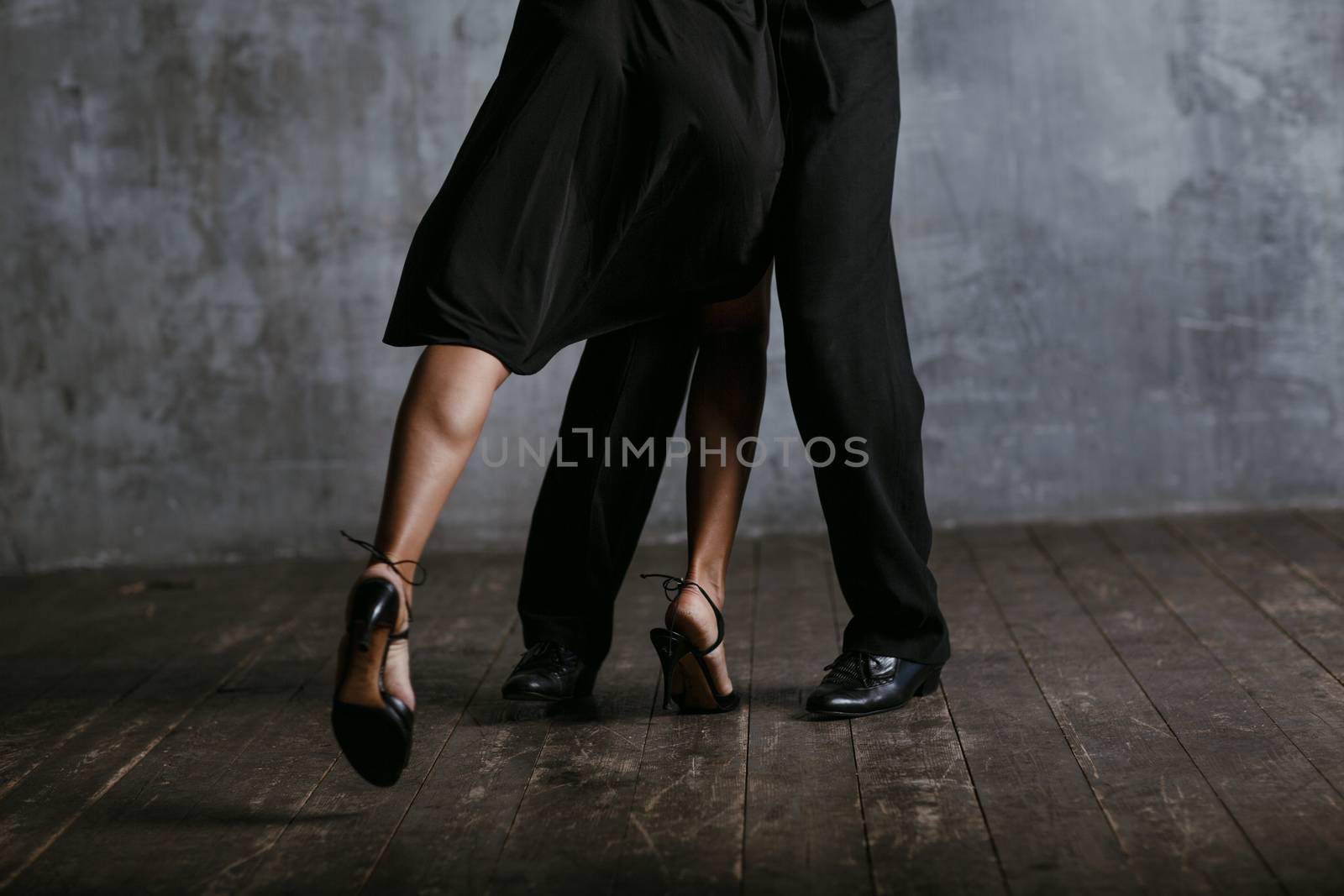 Young pretty woman in black dress and man dance tango legs close up by primipil