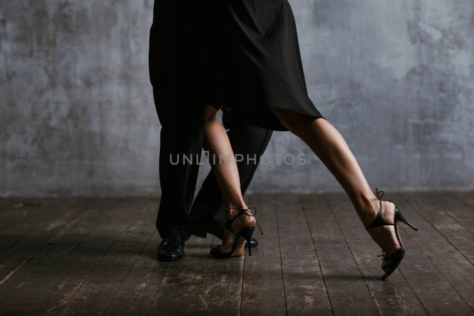 Young pretty woman in black dress and man dance tango