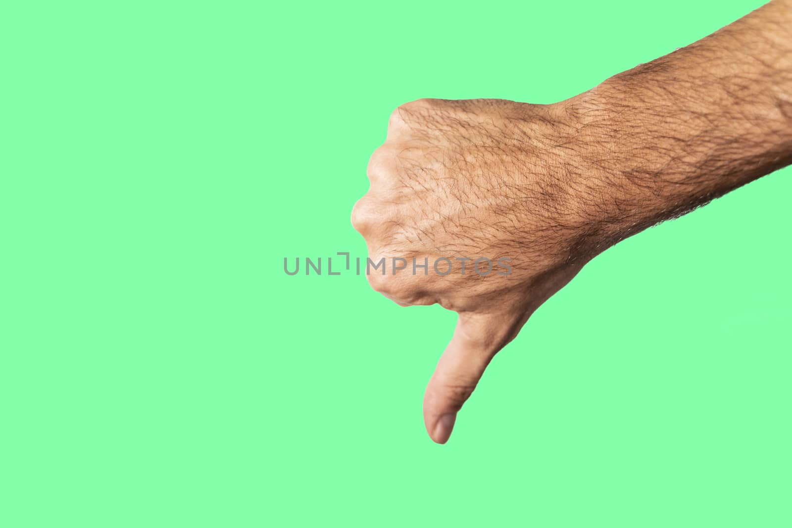 Thumb down hand sign isolated on a green background.