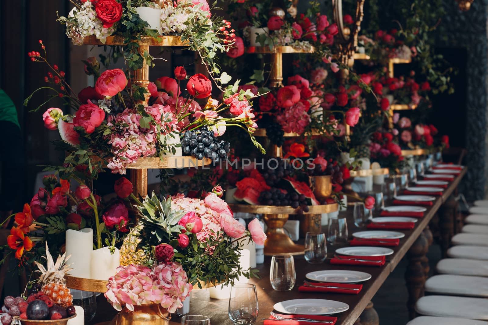 Wedding table flowers with fruits and berries decor in red white pink green colors.