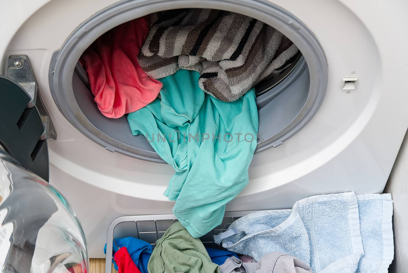 white front-loading washing machine, full of clothes. cleaning laundry. dirty laundry in the washing machine