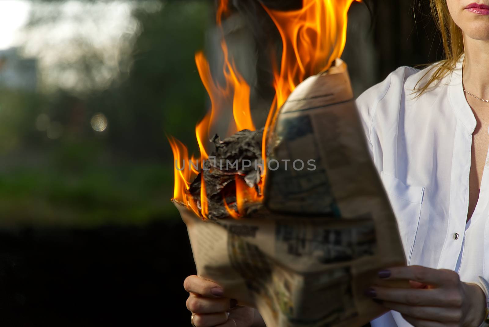 Burning magazine in woman hands. Woman holding burning newspaper. fake news, breaking news concept. selective focuse