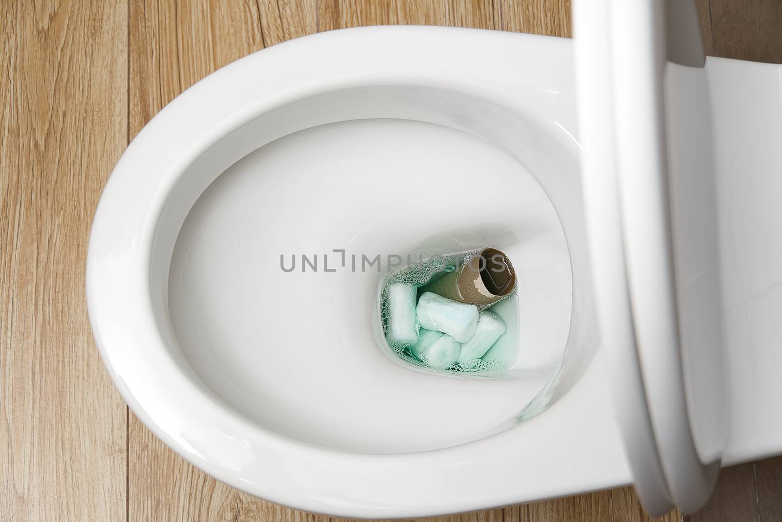 Close-up of a toilet clogged with hygiene products and toilet paper