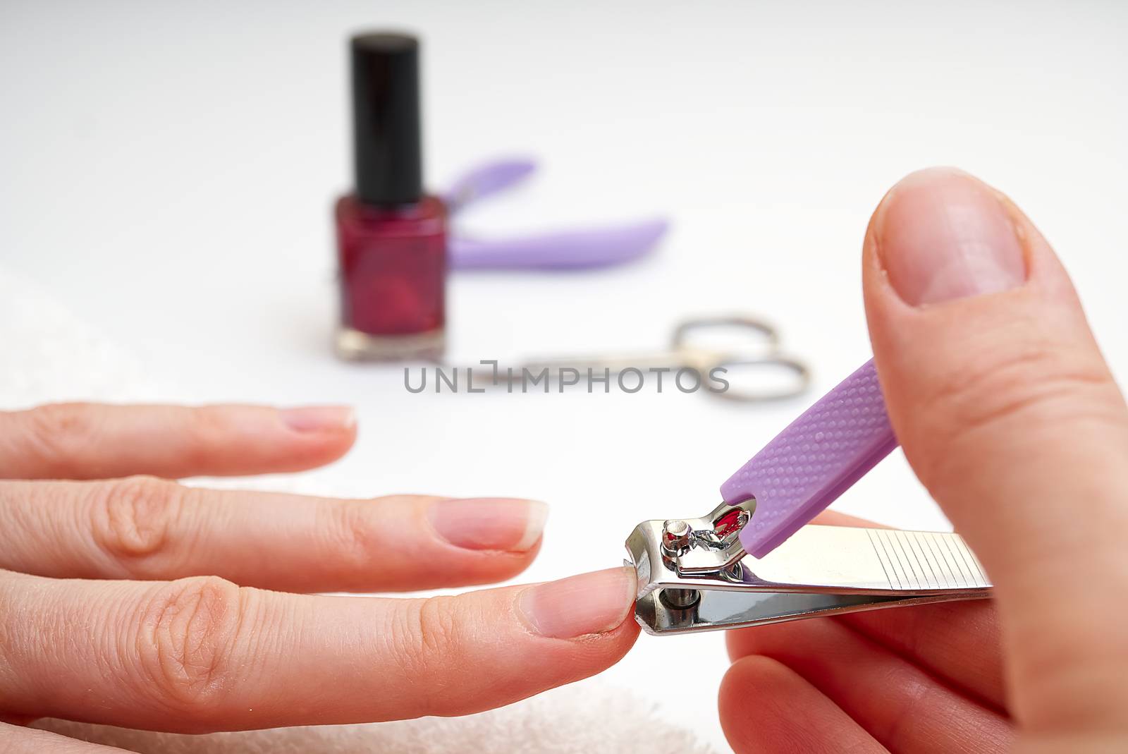 Woman Clipping Nail s with Forceps. Female cuts his nails on a white background with tweezers for nails. manicure procedures yourself at home by PhotoTime