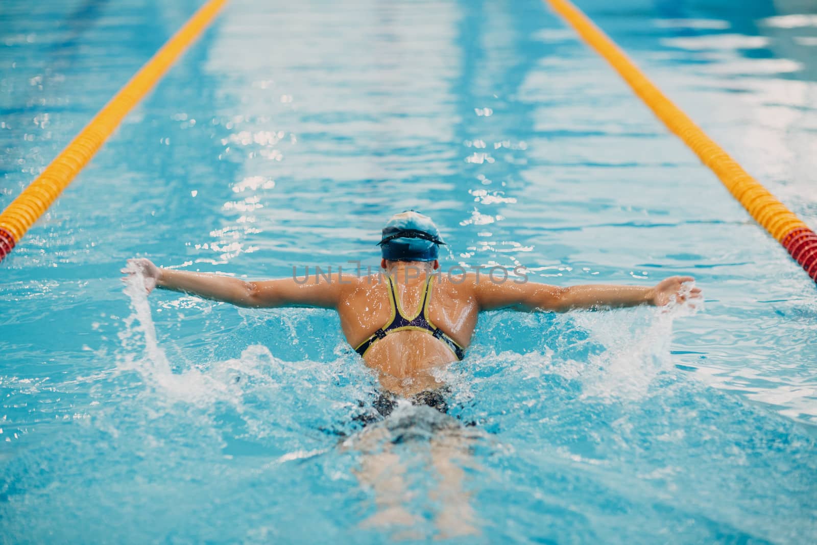 Young woman swimmer swims in swimming pool by primipil