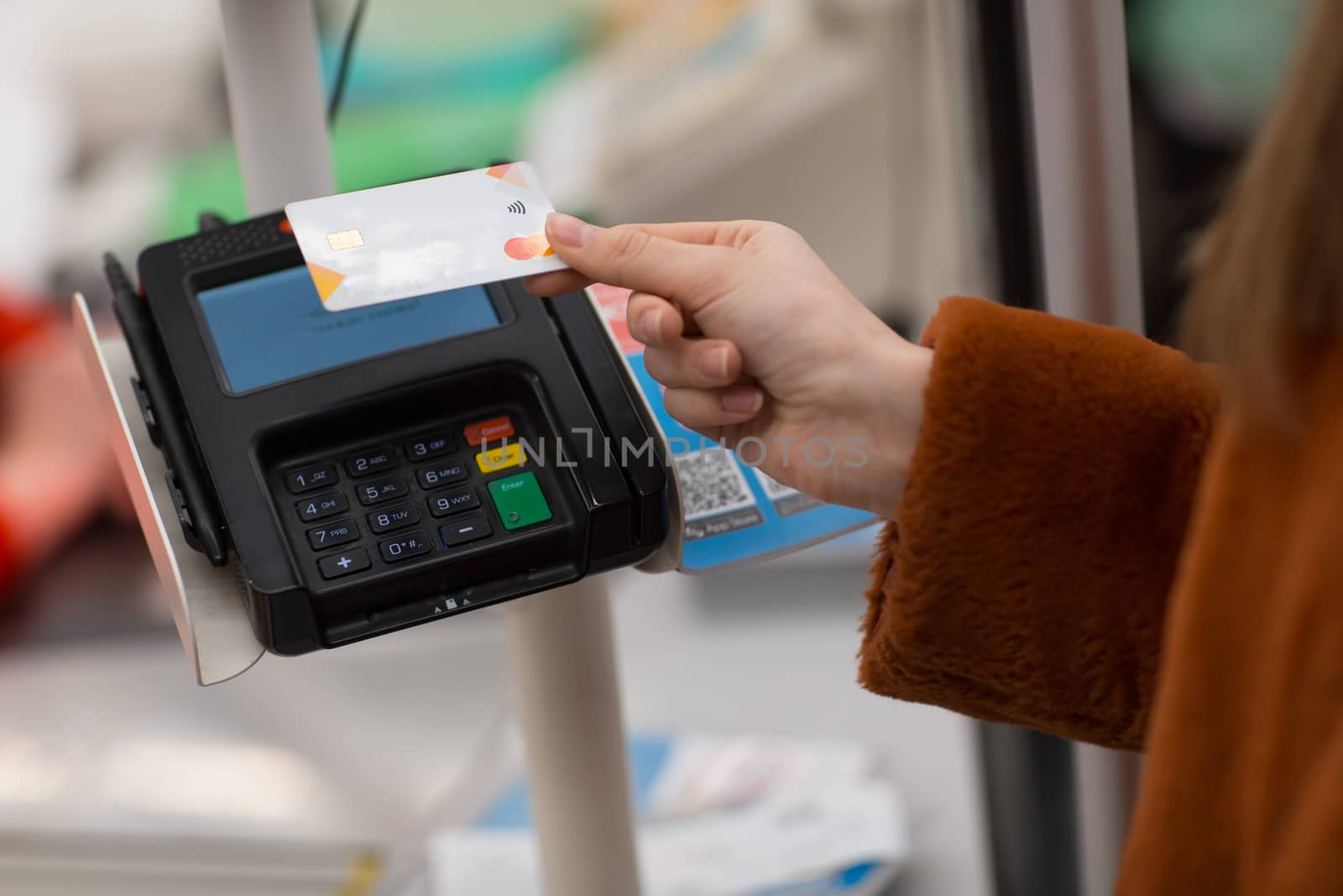 Young woman with a credit card pays for purchases at the checkout counter in the store by primipil