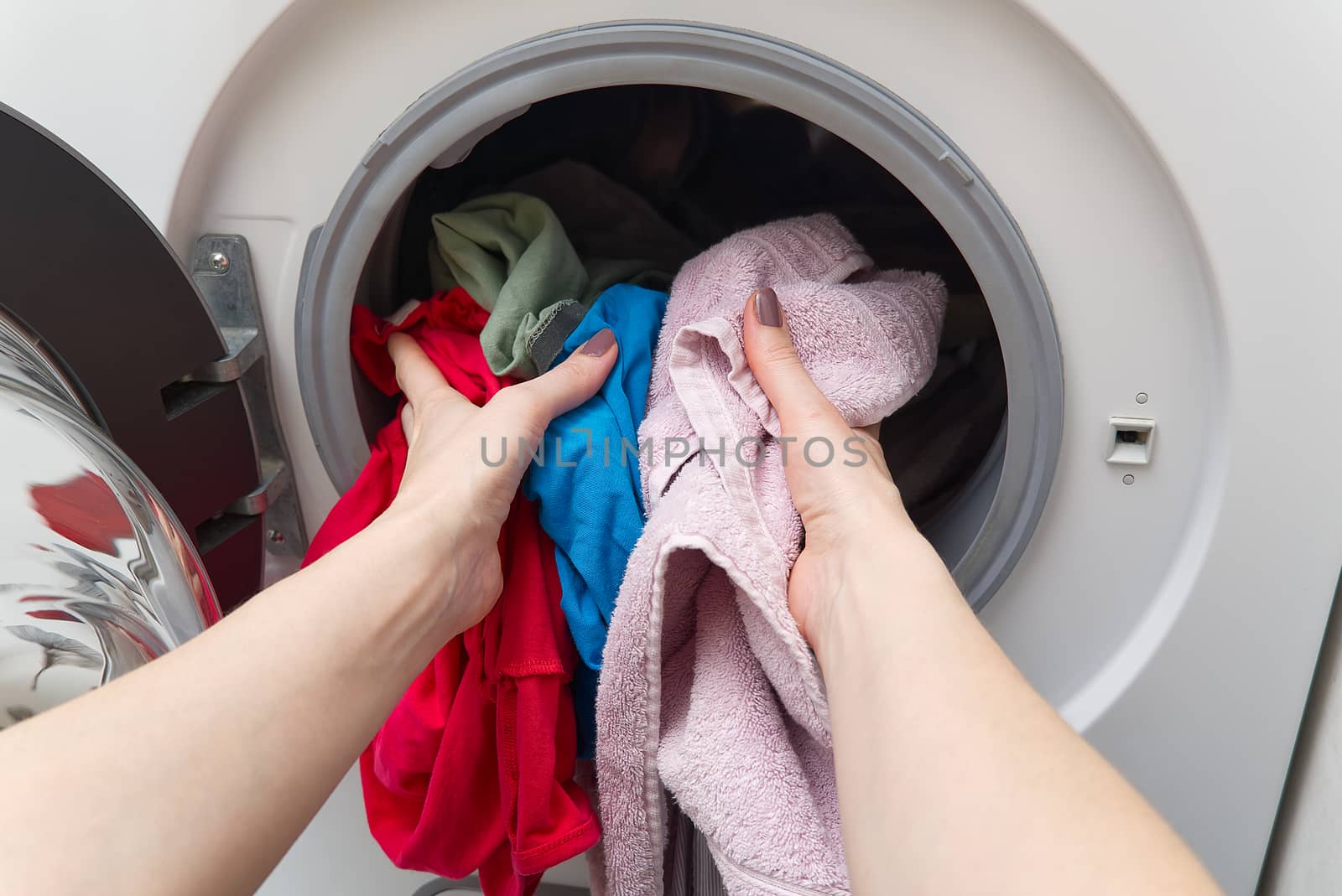 white front-loading washing machine, full of clothes. cleaning laundry. dirty laundry in the washing machine