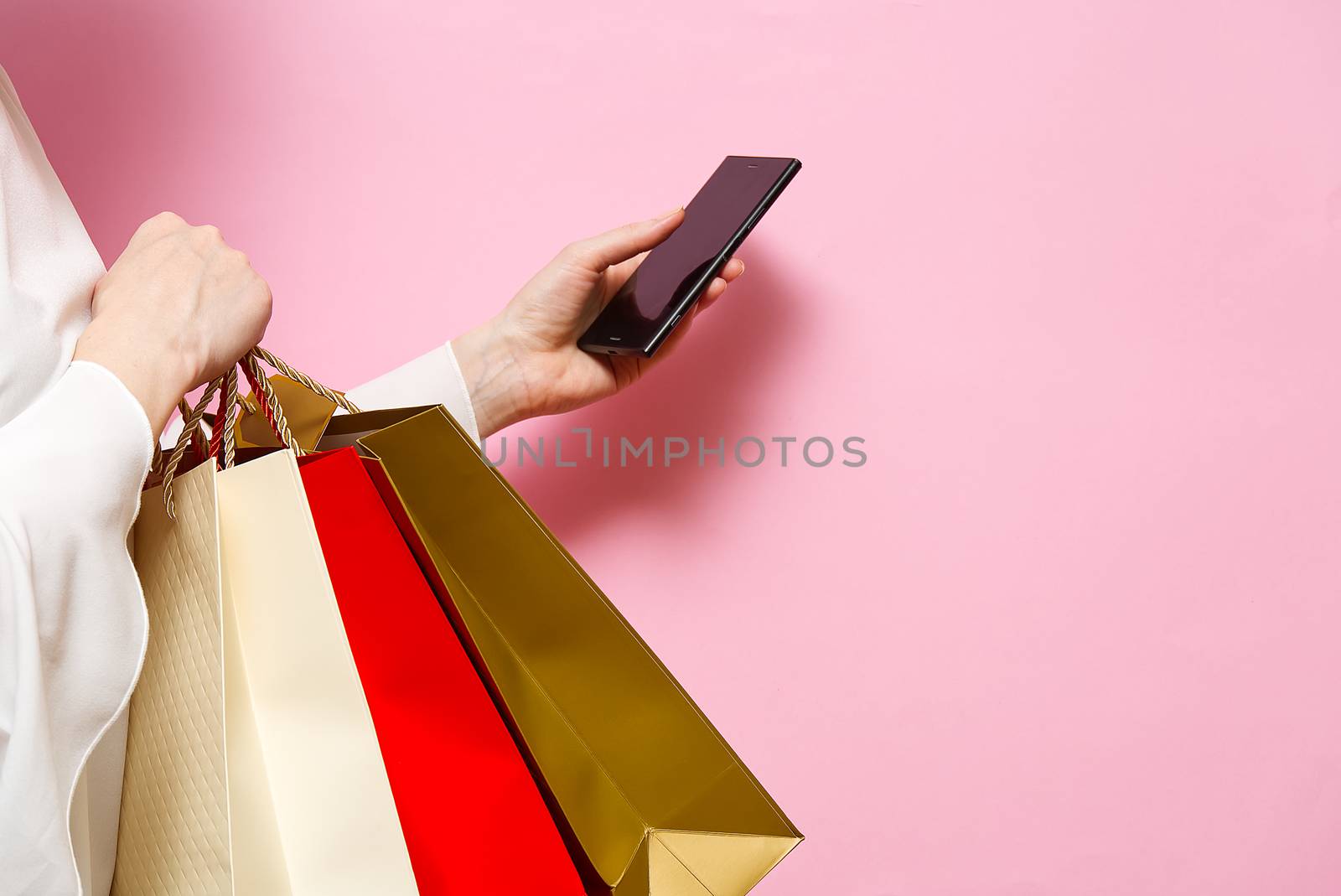Women hand holding modern mobile phone for online shopping. white screen on a screen. Online shopping concept with smartphone. Women on pink background. by PhotoTime