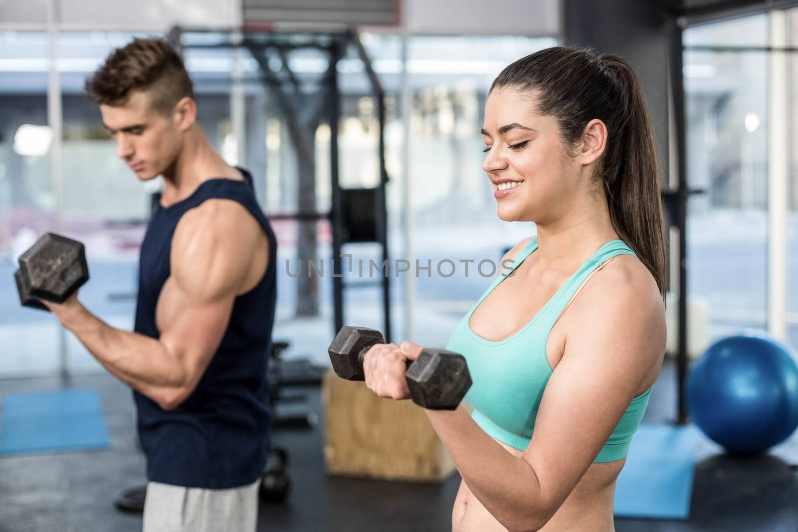 Fit people lifting dumbbells at gym