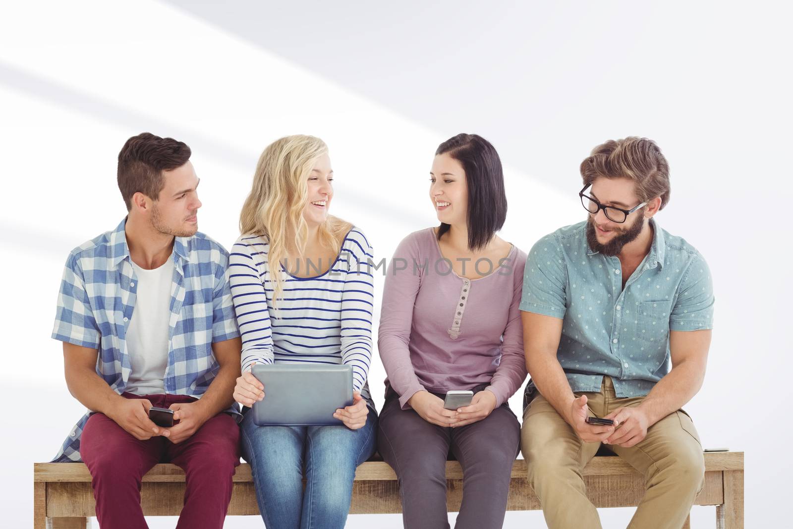 Smiling business people holding electronic gadgets while sitting on desk  against grey vignette