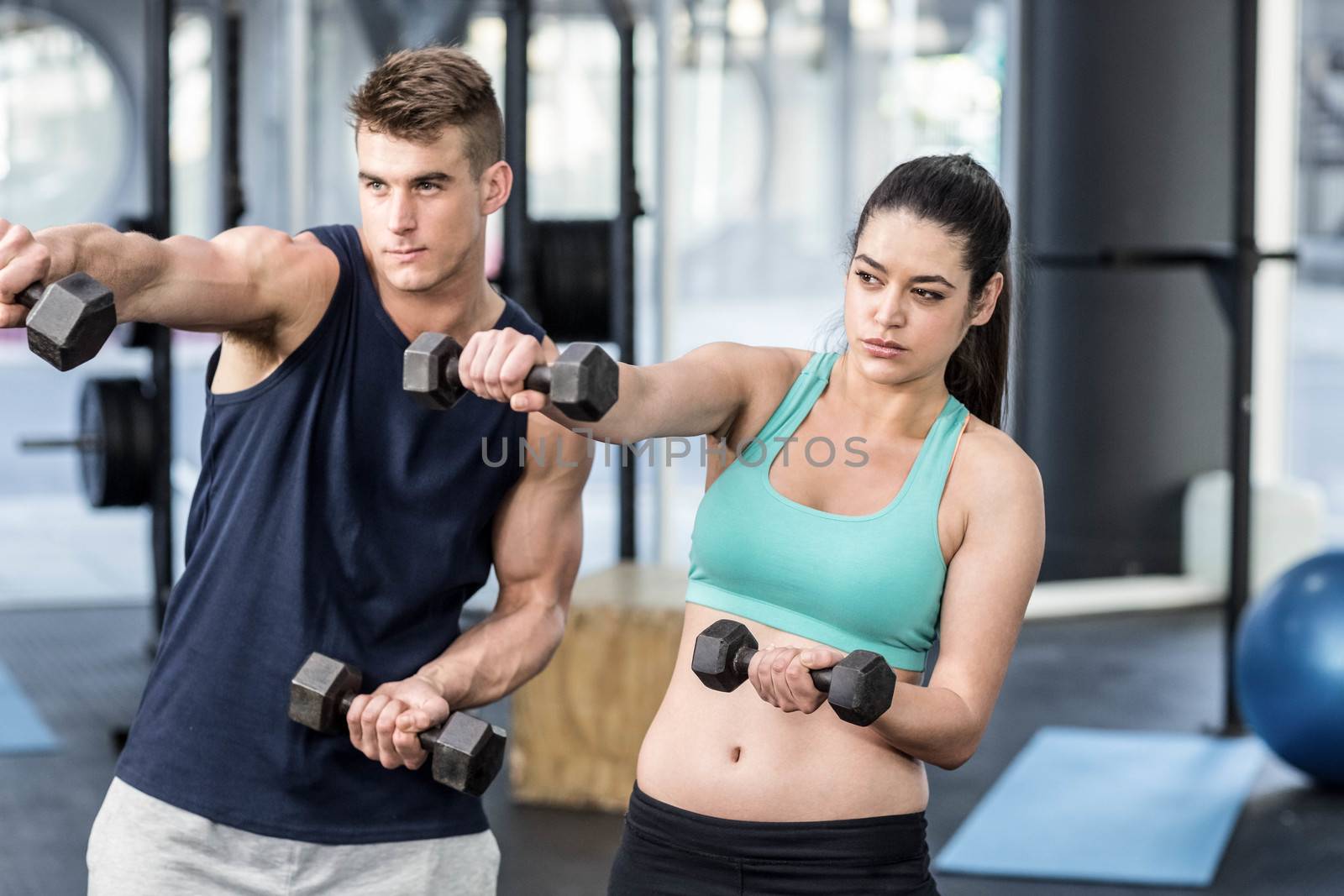 Fit people lifting dumbbells at gym