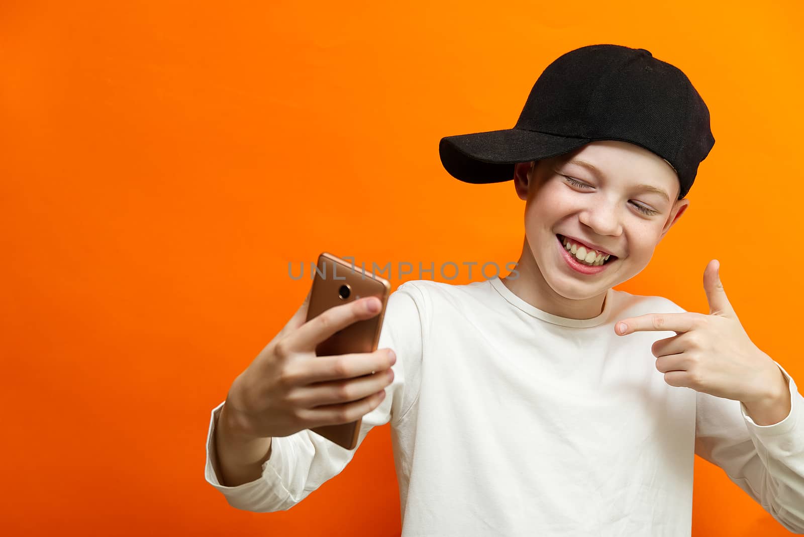 Social distancing and Online communication concept, Happy boy Chatting with friend by smartphone on orange wall background. Happiness in distancing concept