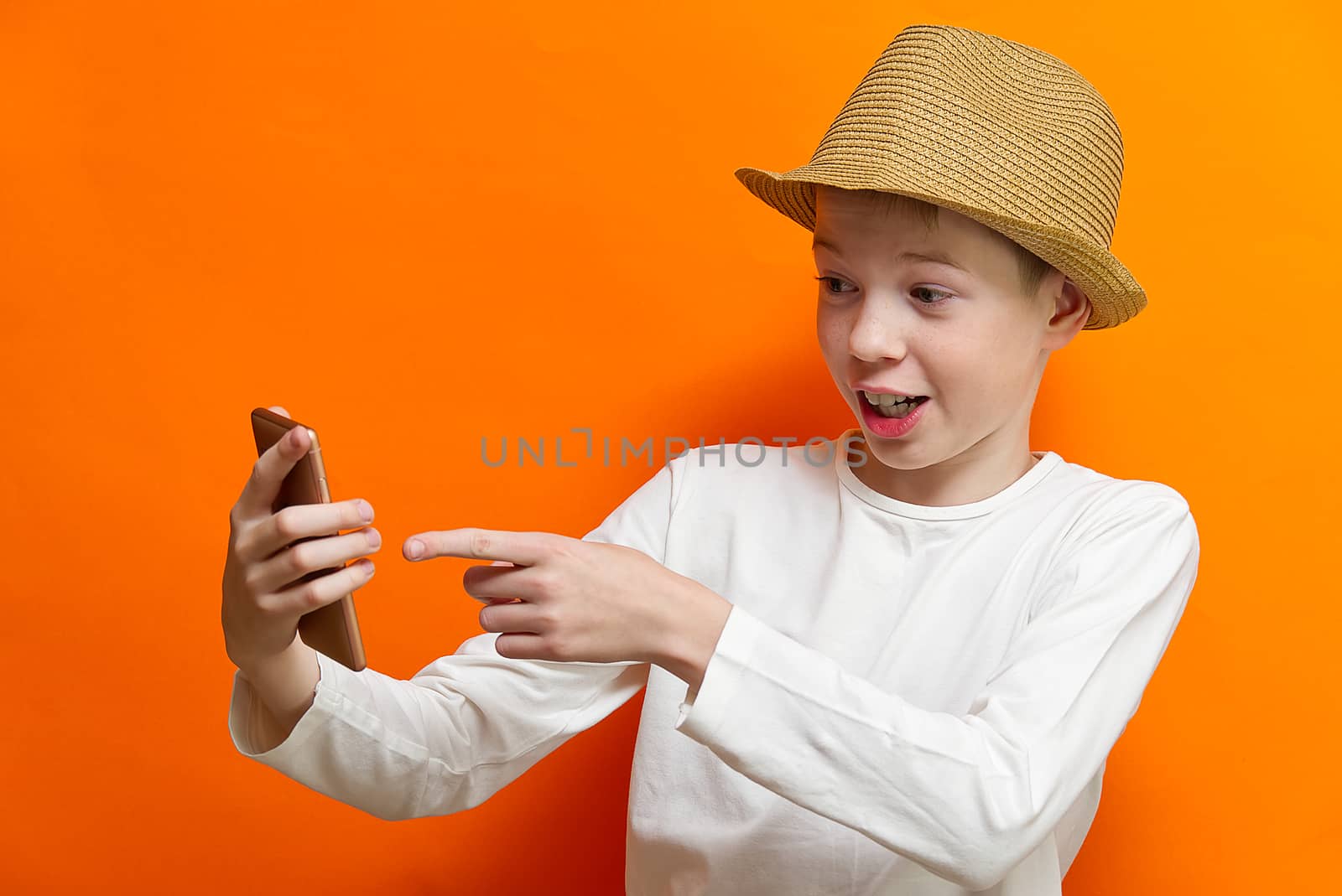 Social distancing and Online communication concept, Happy boy Chatting with friend by smartphone on orange wall background. Happiness in distancing concept. by PhotoTime