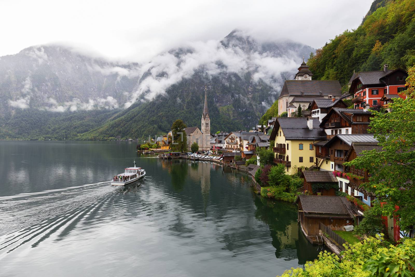 Scenic picture-postcard view of famous Hallstatt lakeside town in the Austrian Alps with passenger ship in beautiful morning light at sunrise on a sunny day in summer, Salzkammergut region, Austria