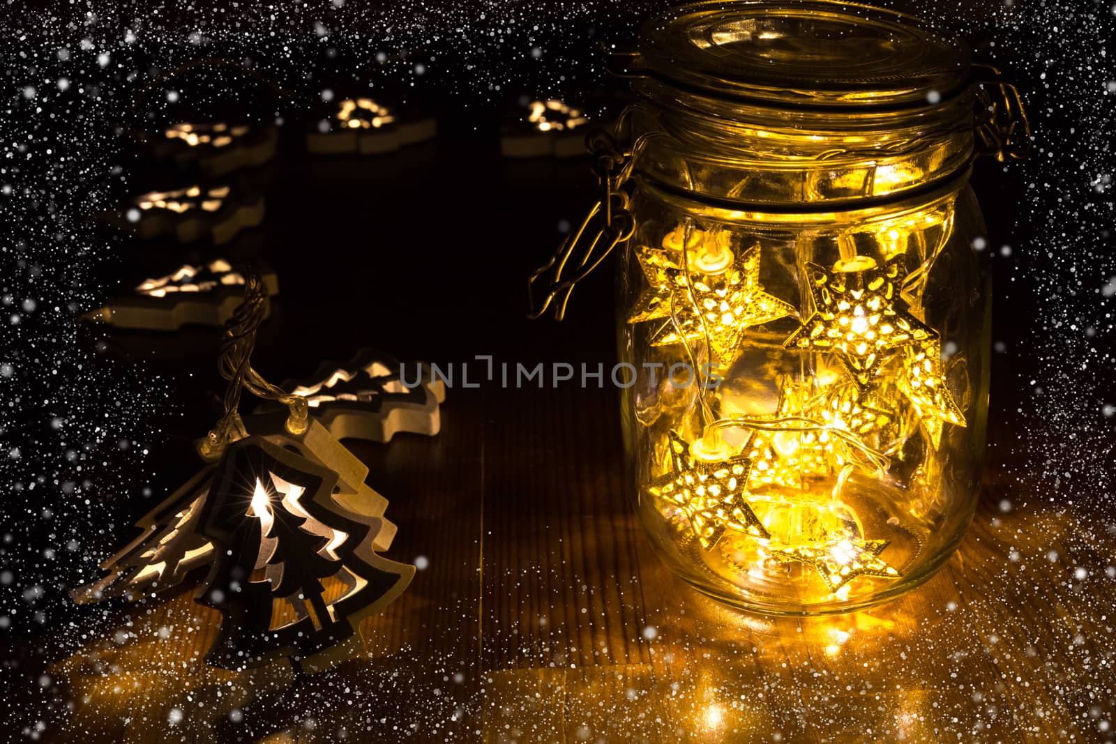 Christmas lights in a jar on the wooden table with snow frame