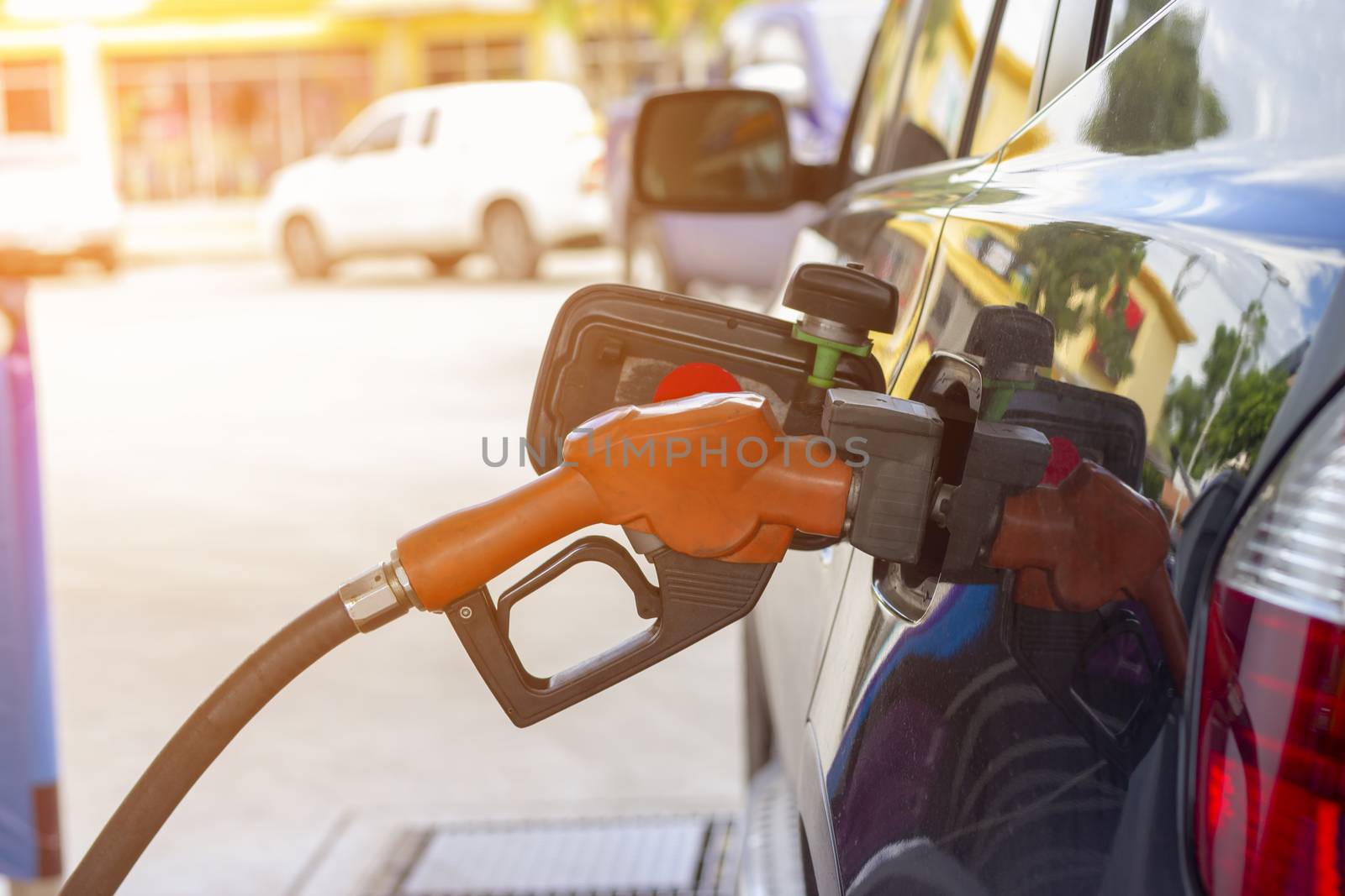 fuel nozzle. Filling gasoline to black car at gas station