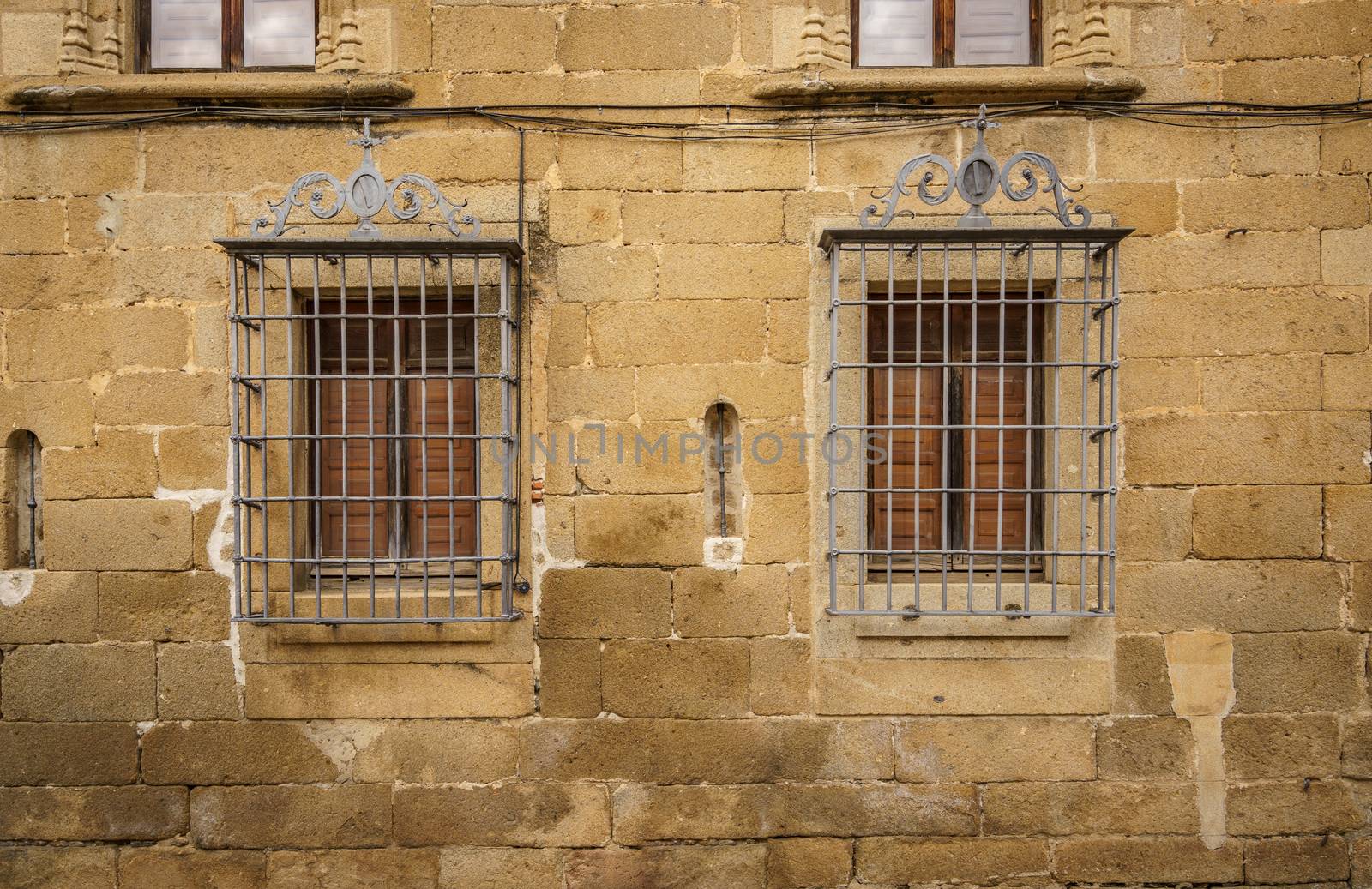Window with bars on a stone facade in old medieval town of Plasencia, Spain by tanaonte