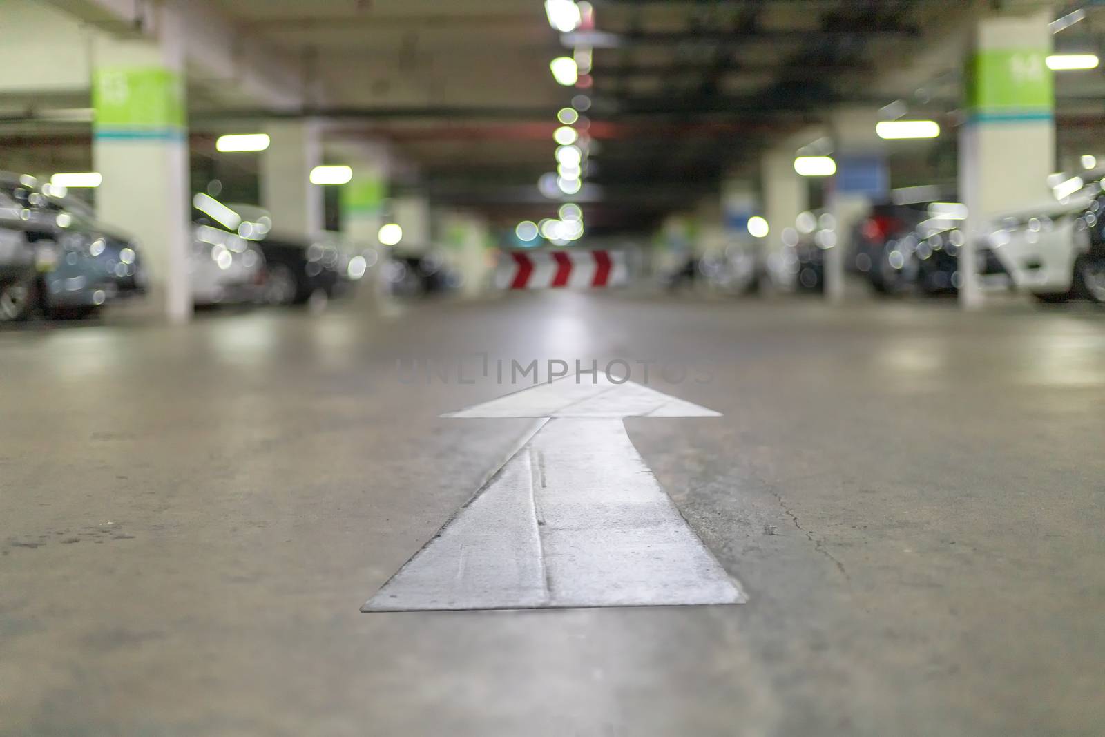 Underground parking at supermarket with white arrow sign for exit way. abstract blur image carpark bakcground.