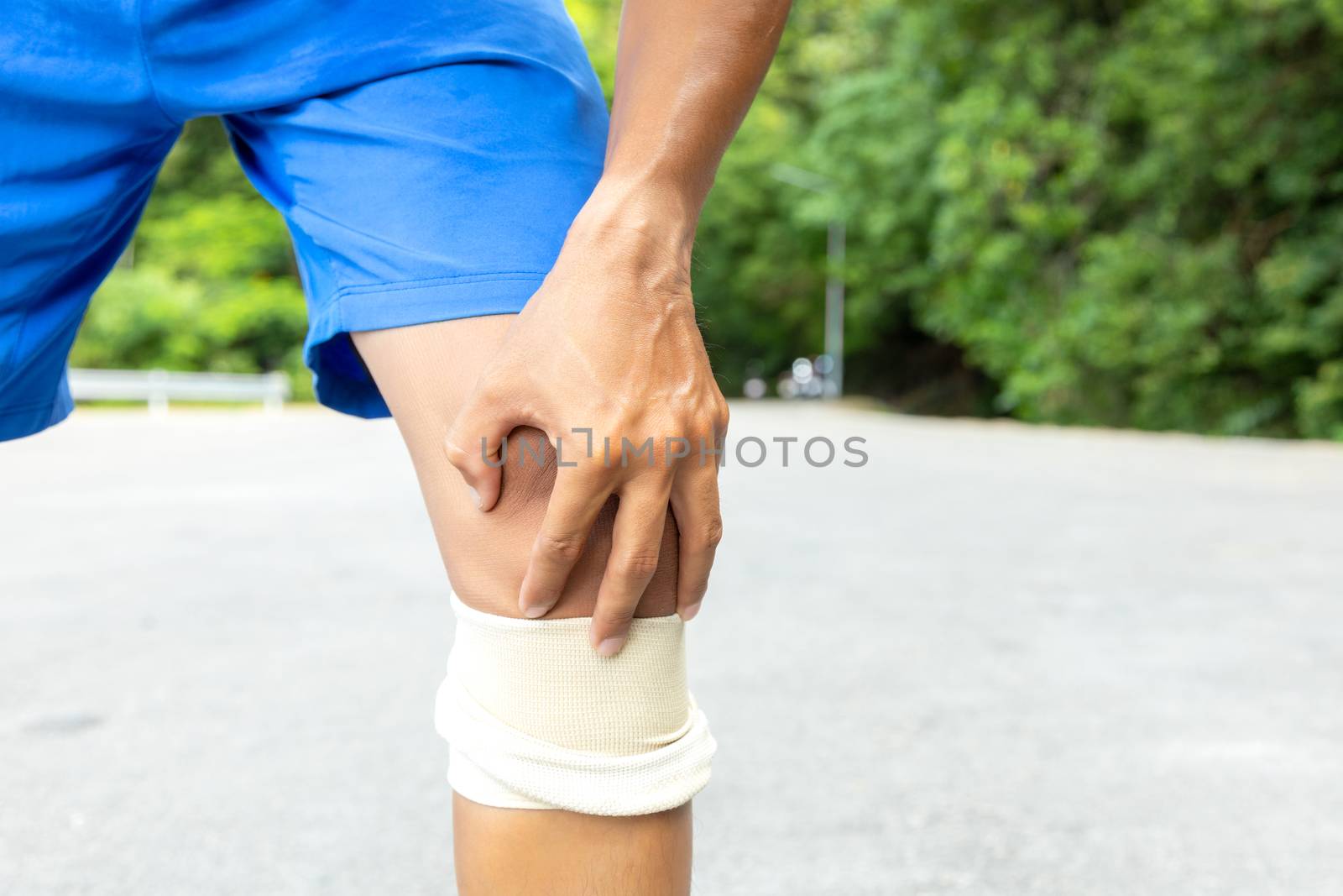 Man with blue runing shorts use hands hold on his knee after run