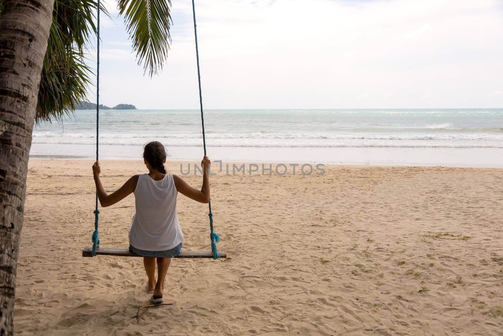 woman traveler sitting on the swing relex on the beach. women tourist enjoy with view of the sea on holiday time. Asia Thailand. With copy space for text or design