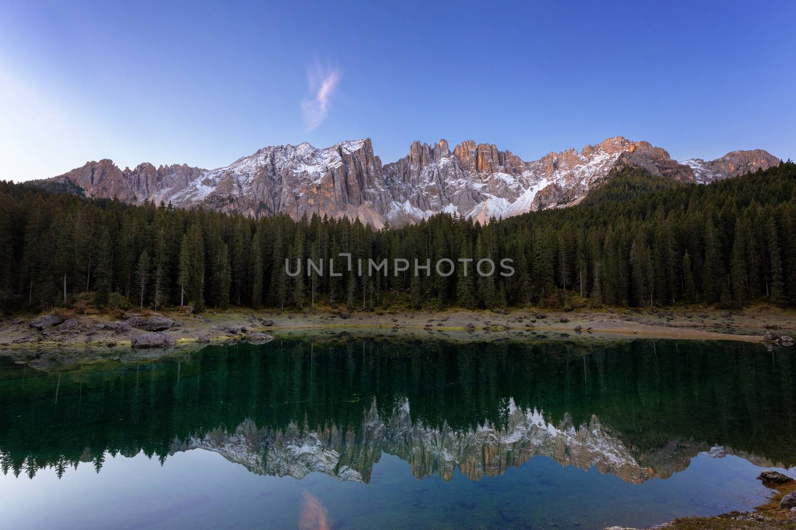 Beautiful sunrise at Carezza lake with light hitting the peaks, Dolomites, Italy