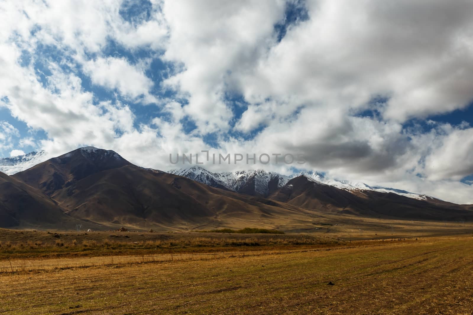 White clouds float over the mountains. Mountain landscape. Kochkor District in the Naryn region of Kyrgyzstan. A 367 highway.
