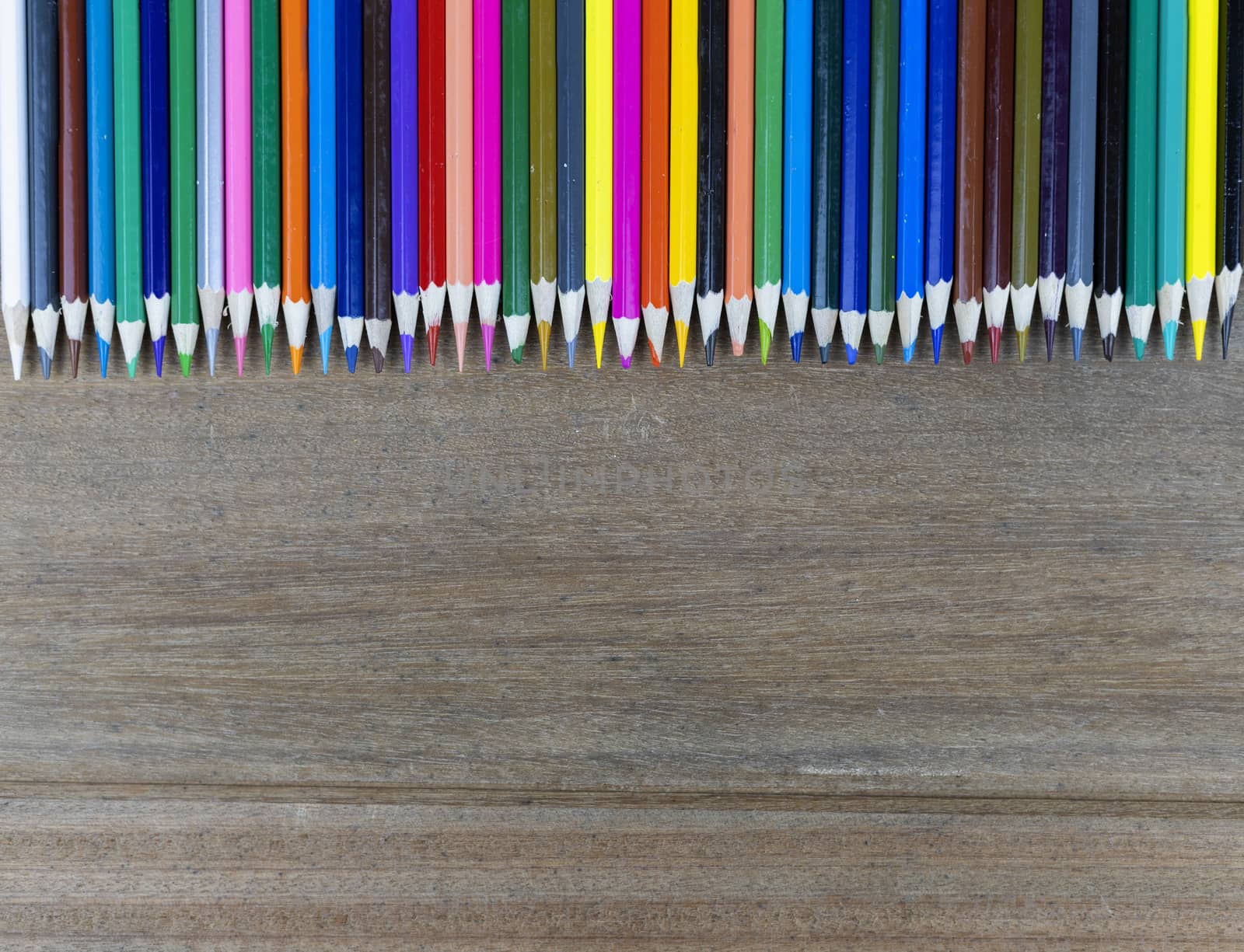 Many color pencils on wood background with copy space for text or design.