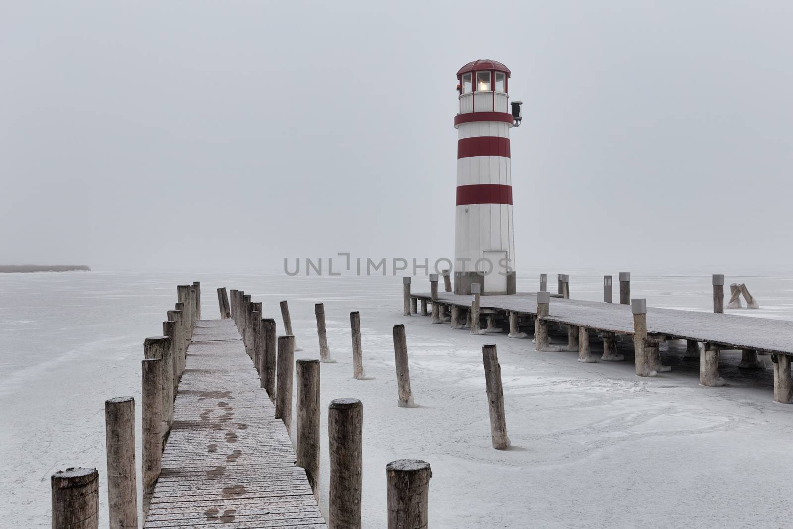 Lighthouse at sunrise with fog and rain during winter