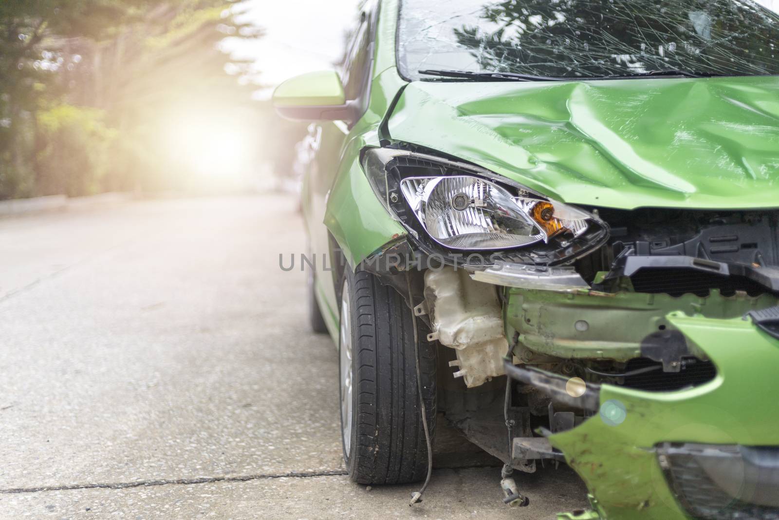 Front of green color car damaged and broken by accident on road parking can not dirve any more