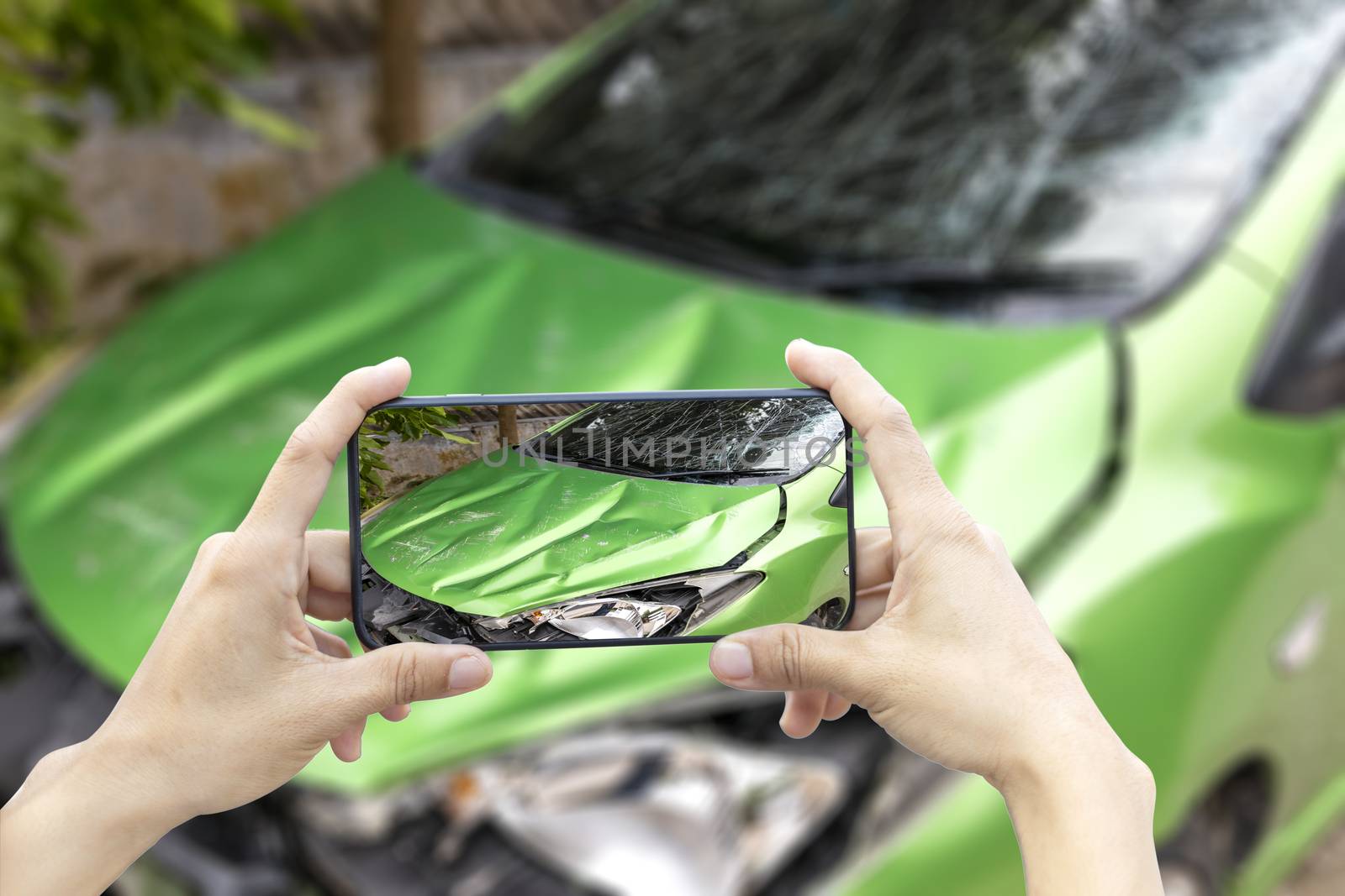 2 hand of woman hold smartphone for take photo of front green color car accident 