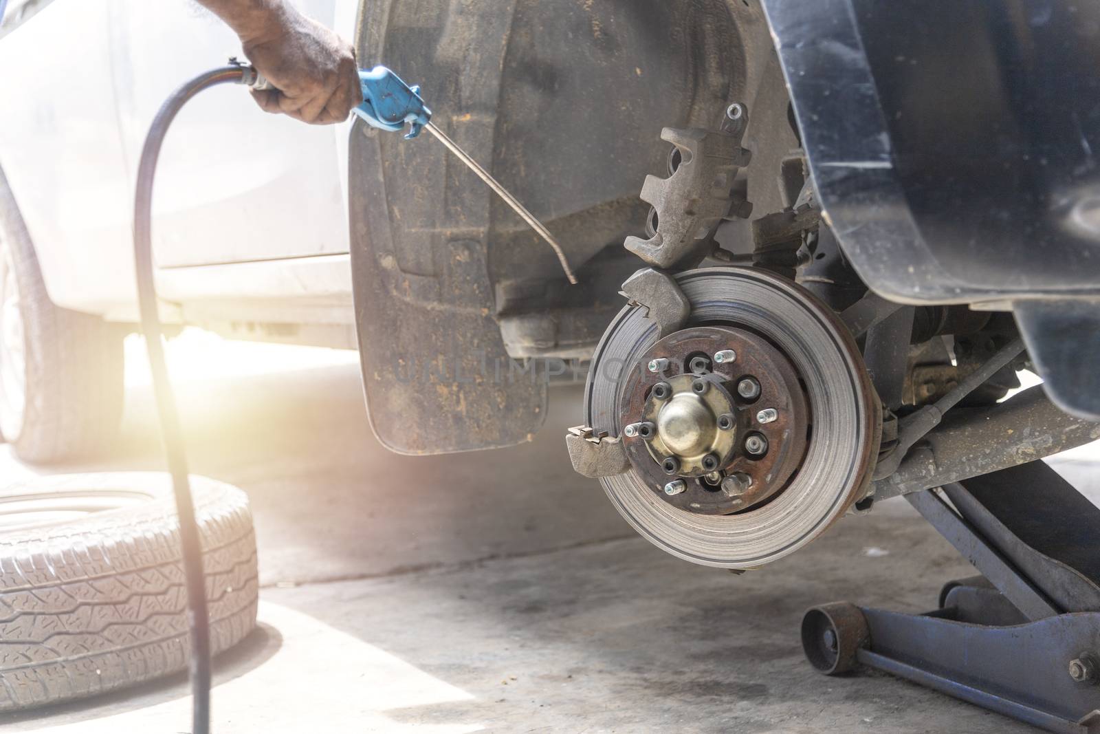 Mechanic use air gun clean disc break take dust removes before change break pat.