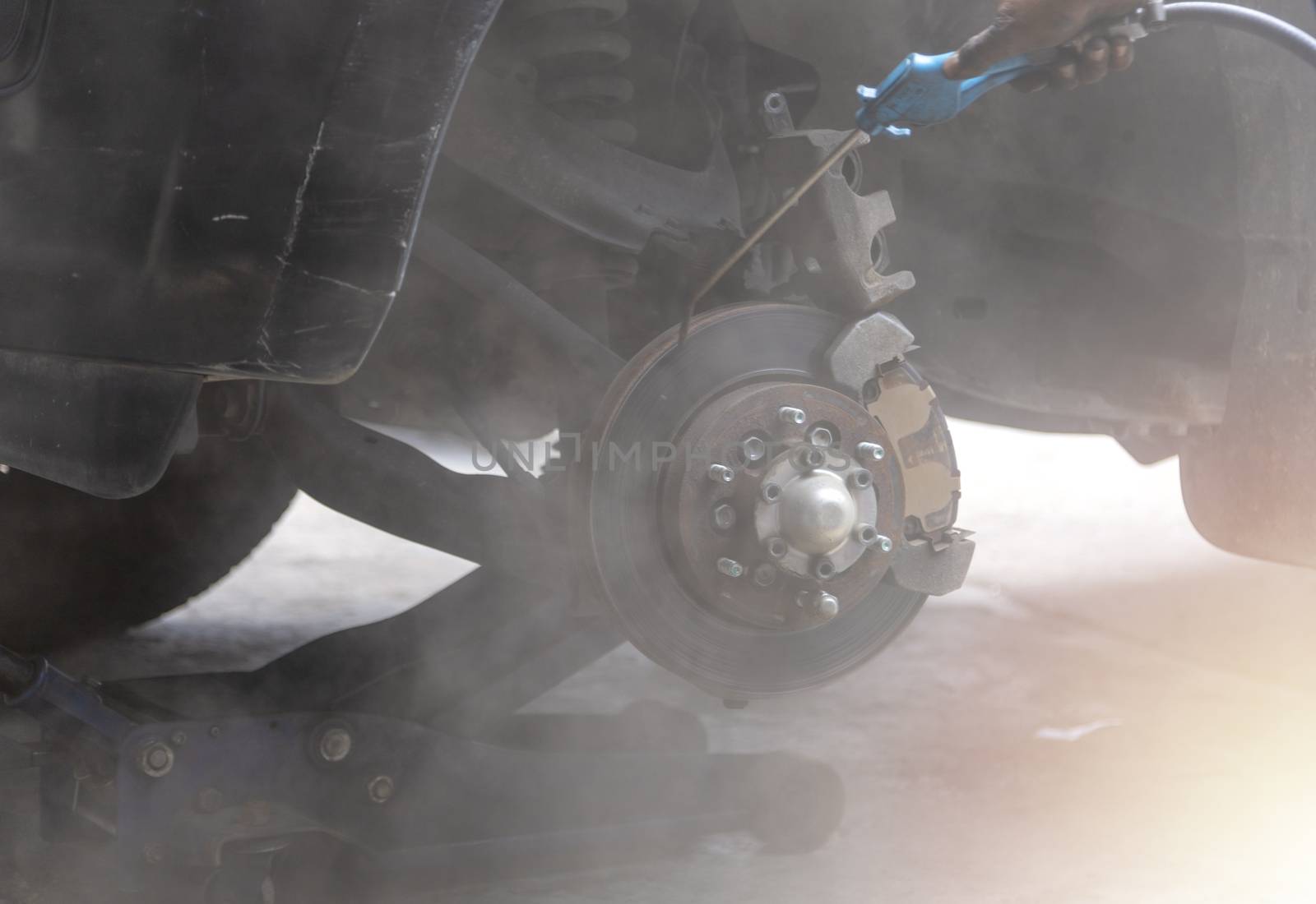 Mechanic use air gun clean disc break take dust removes before change break pat.