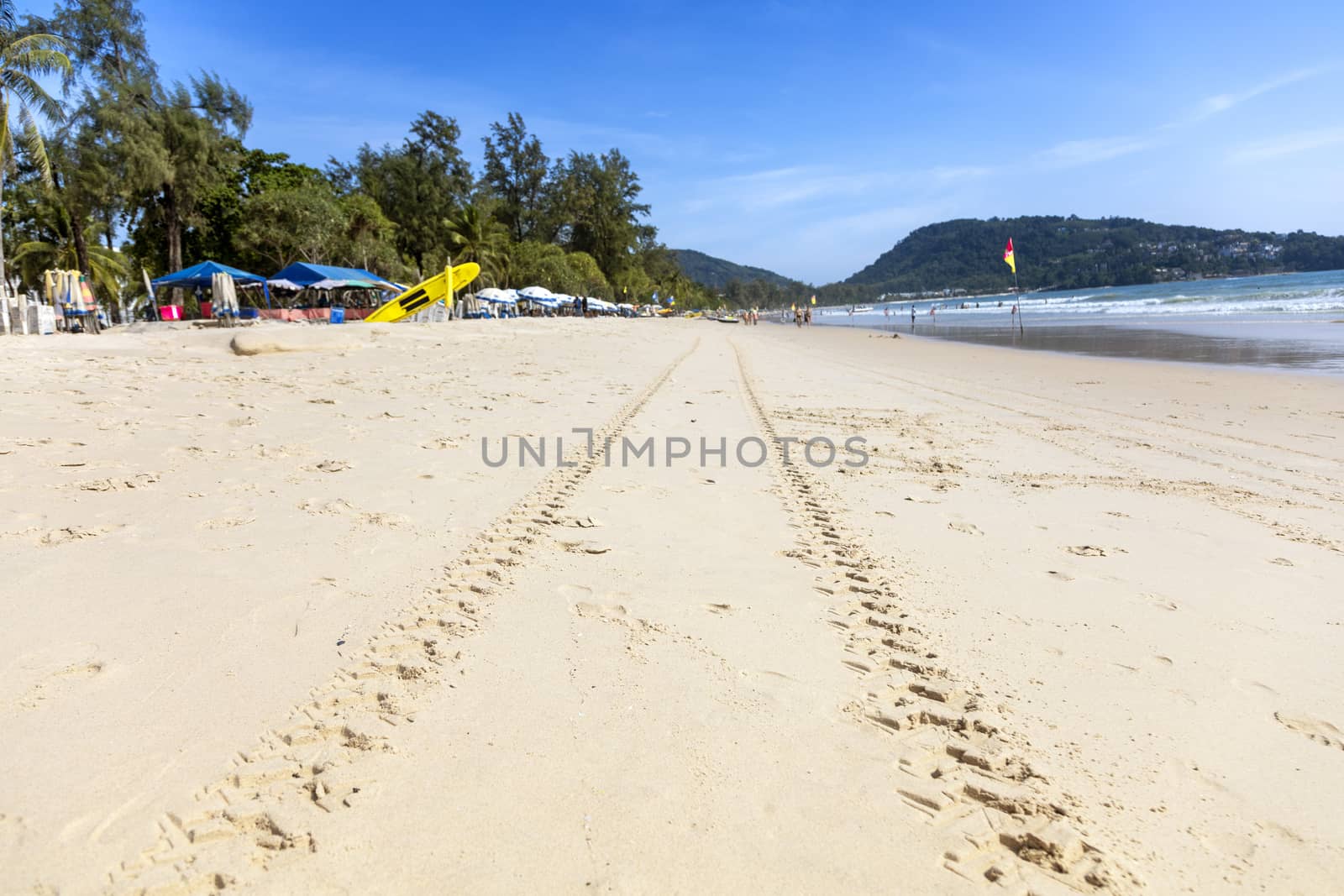 Summer concept. Sand on the beach with clear sky moutain and people play water sea.
