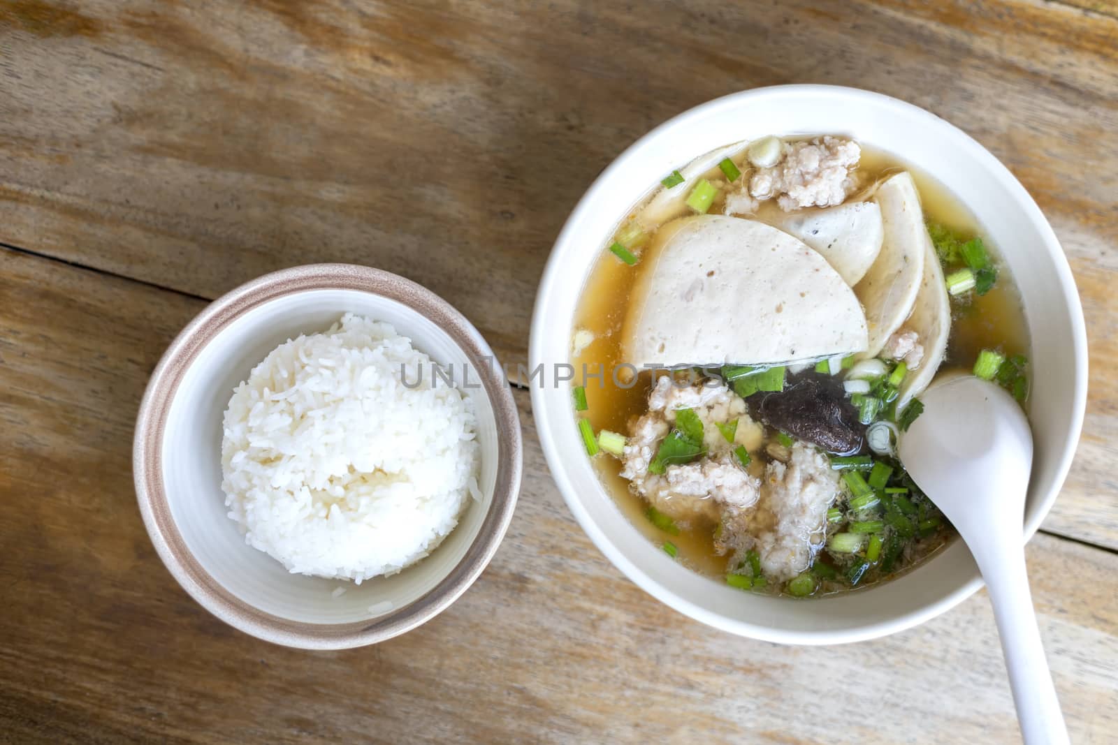 Top view Soup with pock, pock stick, mushroom, vegetable in white bowl near have rice in small bowl on wood table. with copy space for text or design