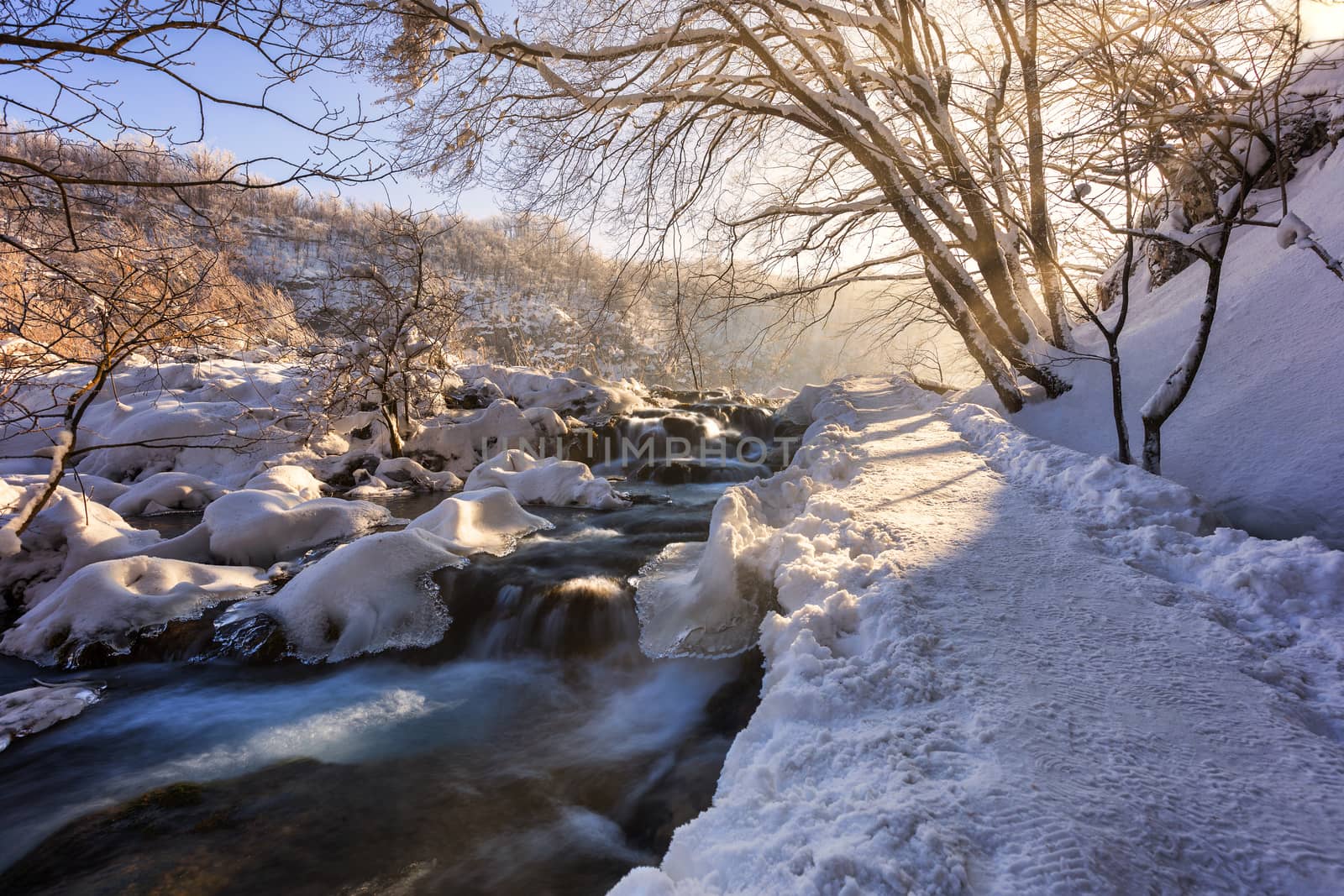 Winter path covered by snow and river flowing thru plitvice lake by necro79