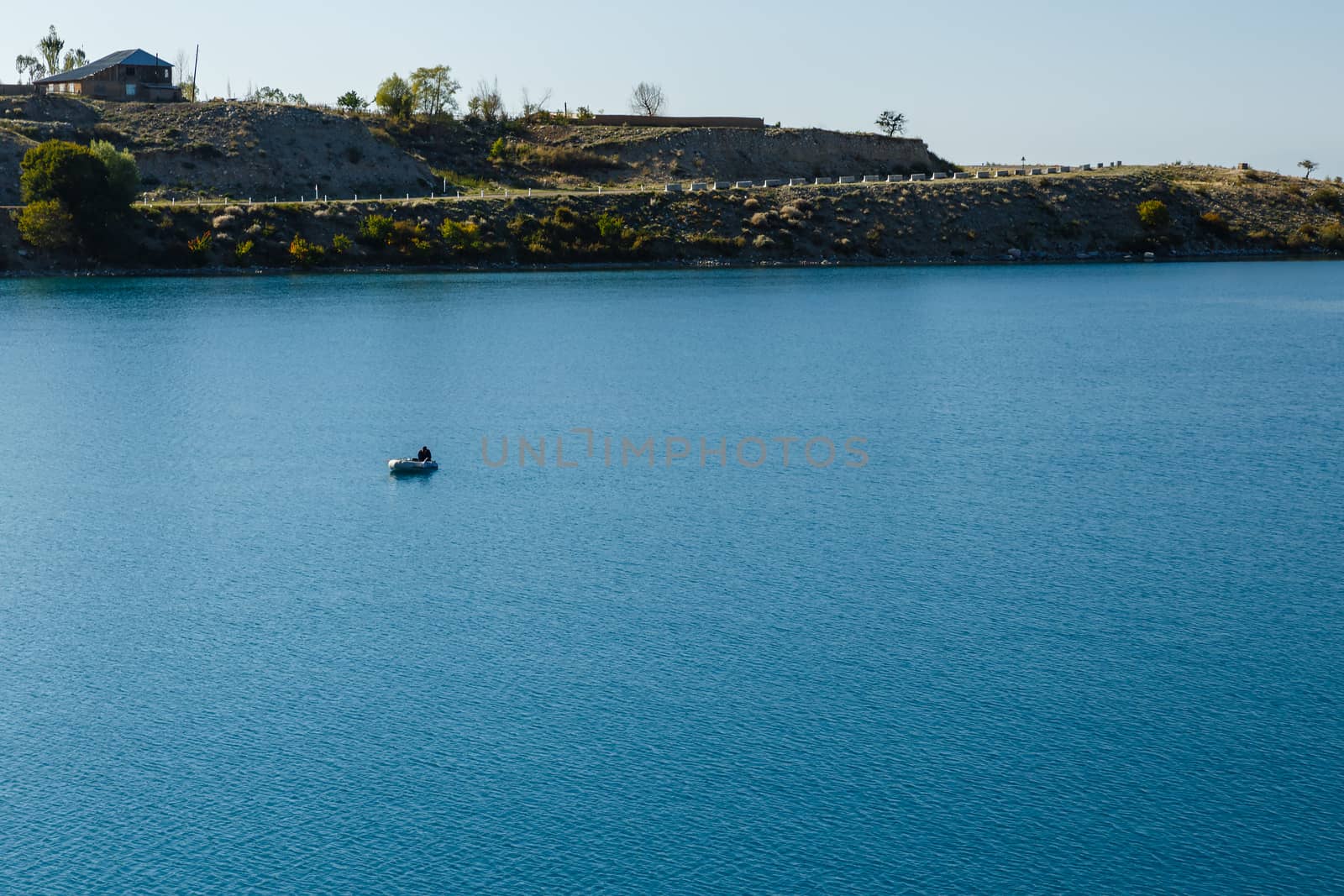 South shore of Issyk-kul lake in Kyrgyzstan, lonely fisherman on a boat on Issyk-Kul Lake
