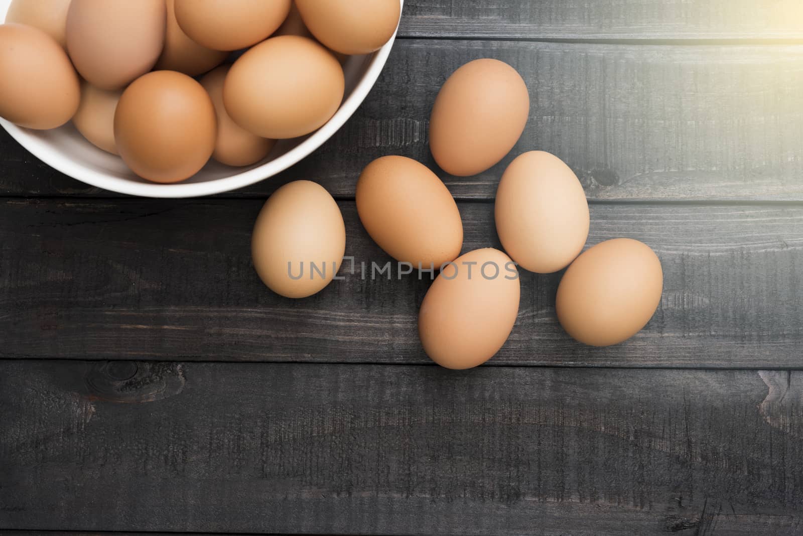 Fresh hen egg in white bowl and 6 hen egg out side on Black color wood table