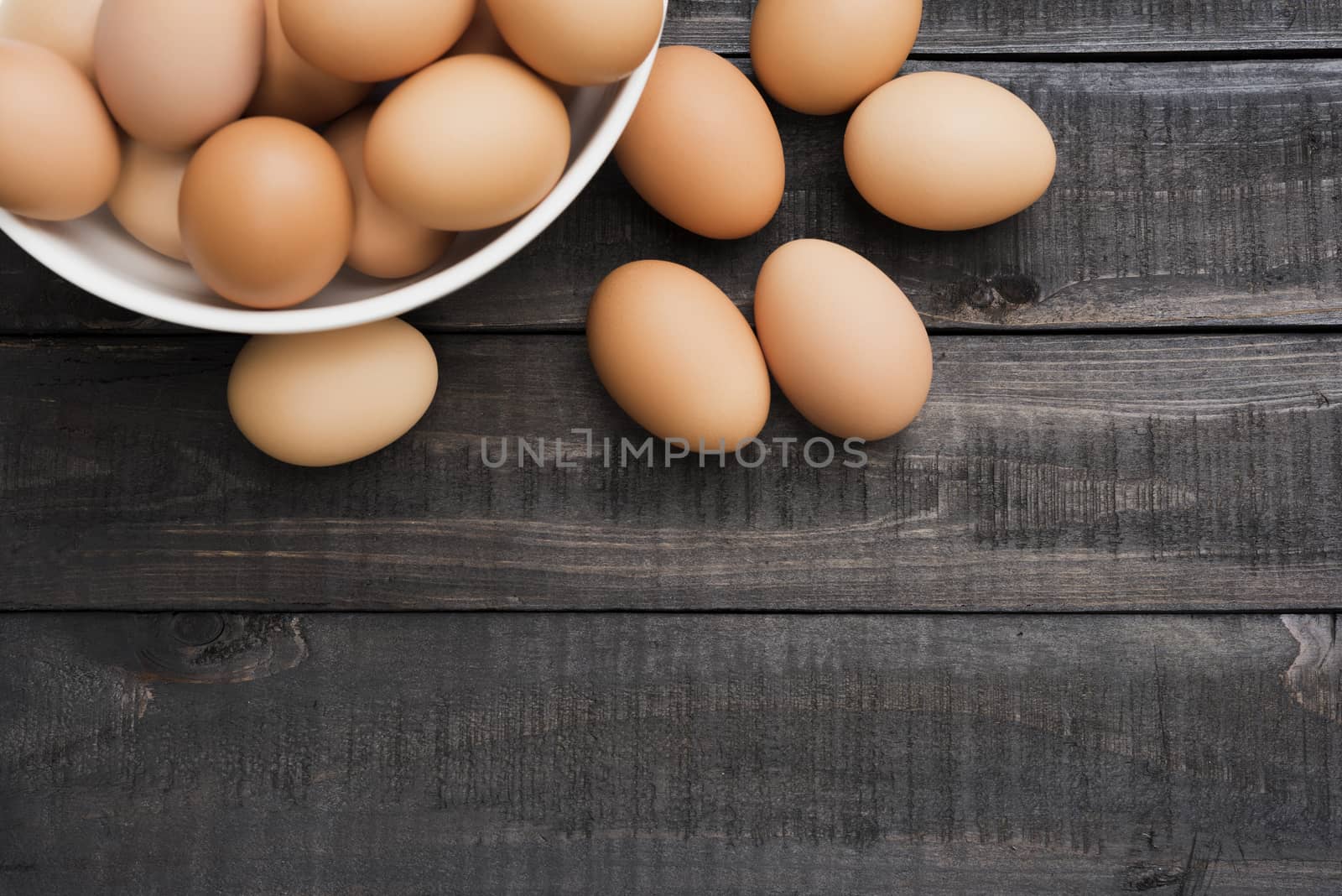 Fresh hen egg in white bowl and 6 hen egg out side on Black color wood table