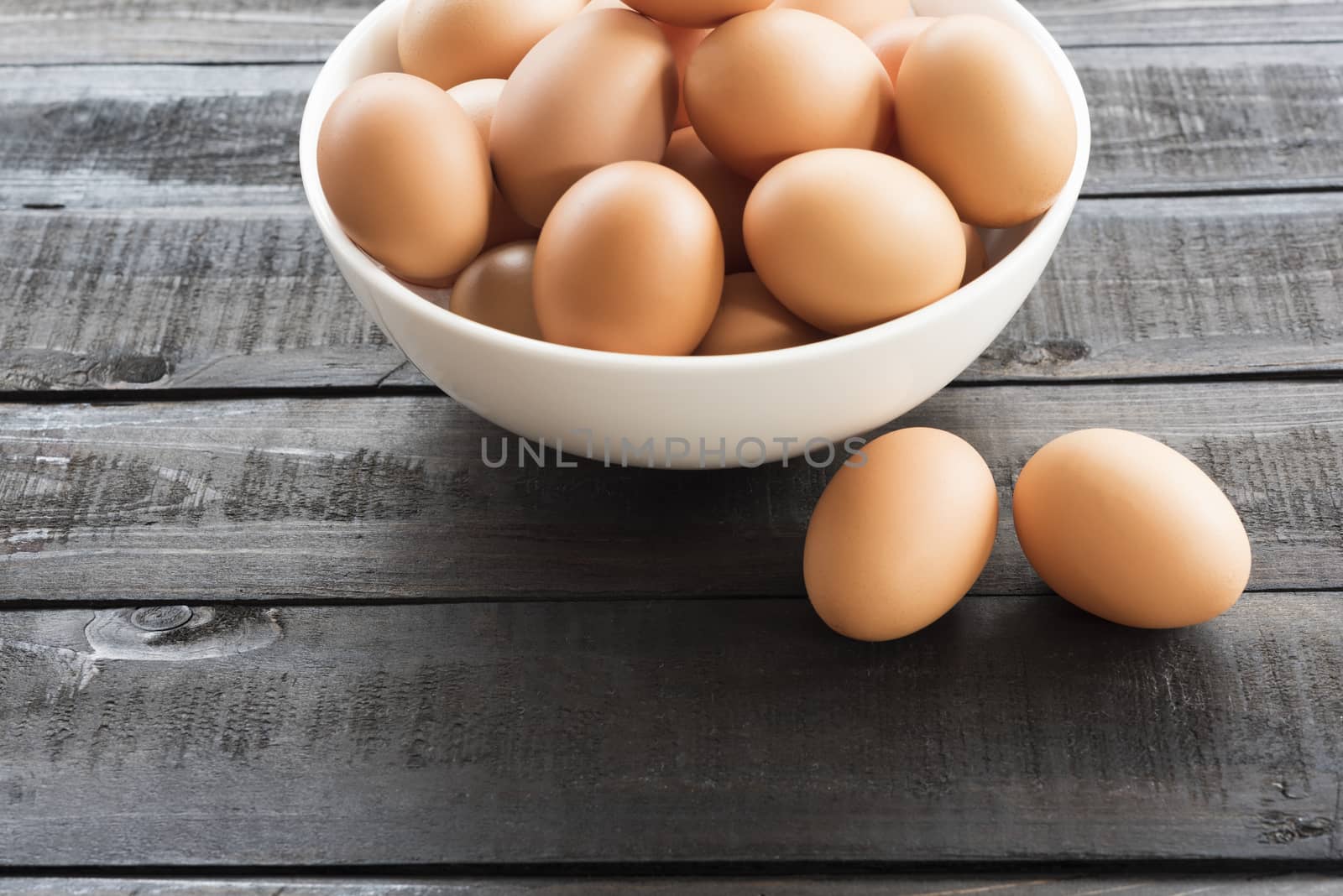 Fresh hen egg in white bowl and 2 hen egg out side on Black color wood table
