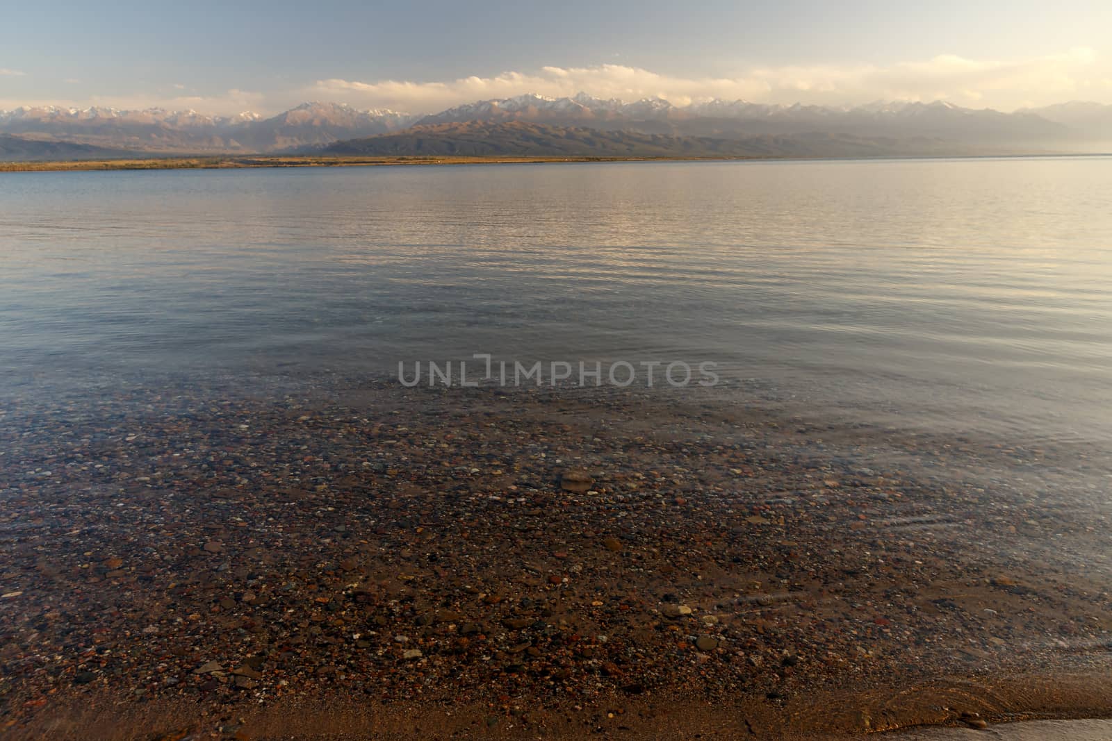 South shore of Issyk-kul lake in Kyrgyzstan, clear water in the lake and mountains with snowy peaks in the background