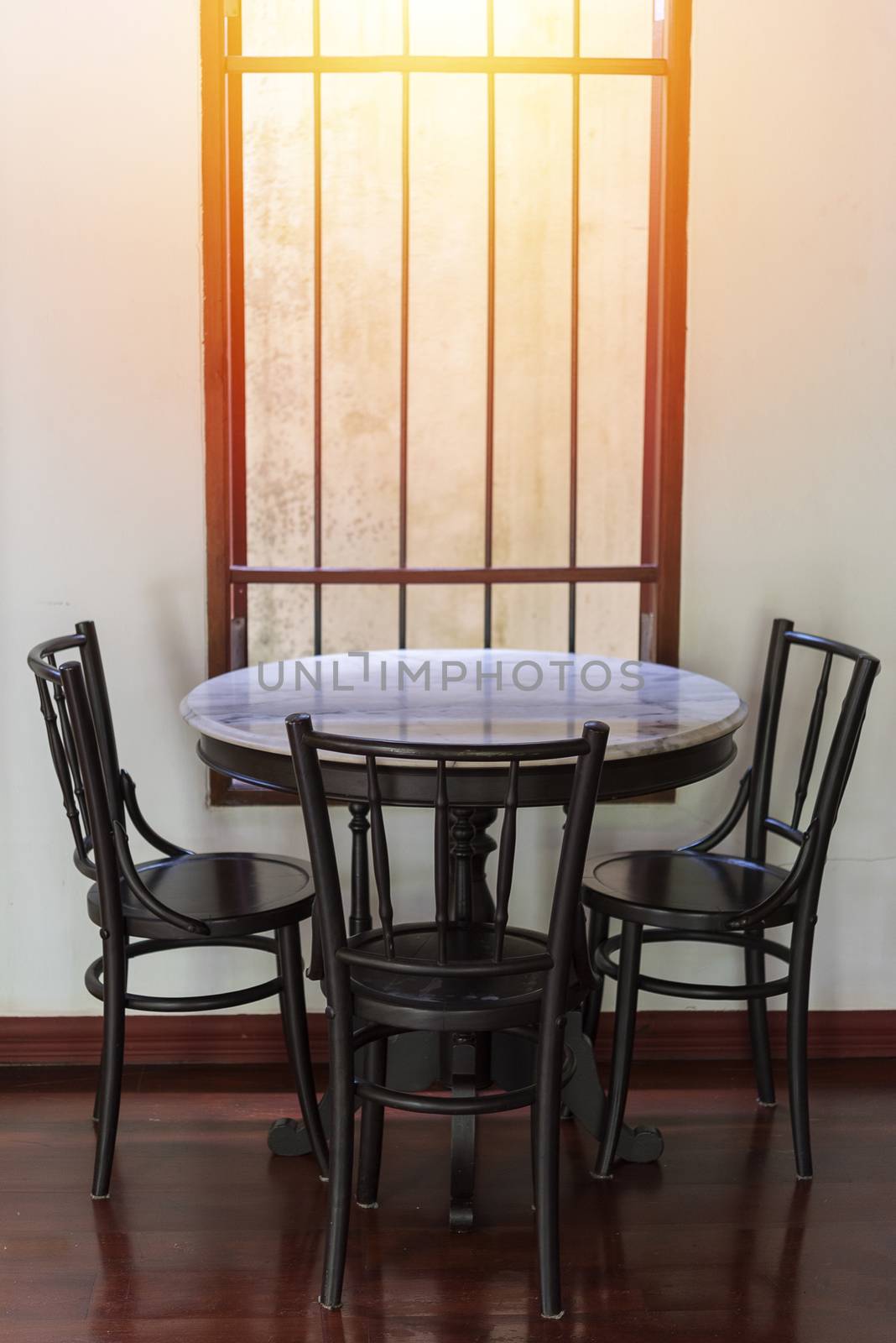 Wooden round table and chair chiness style near window have ray of light on wood floor and white wall 