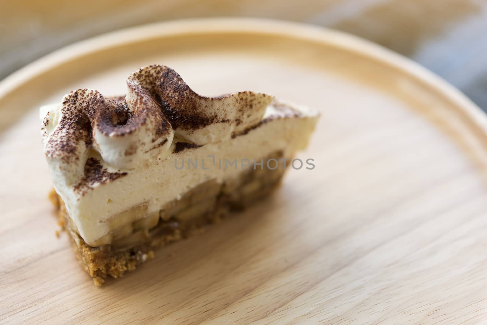 Banoffee pie with chocolate powder on wooden plate