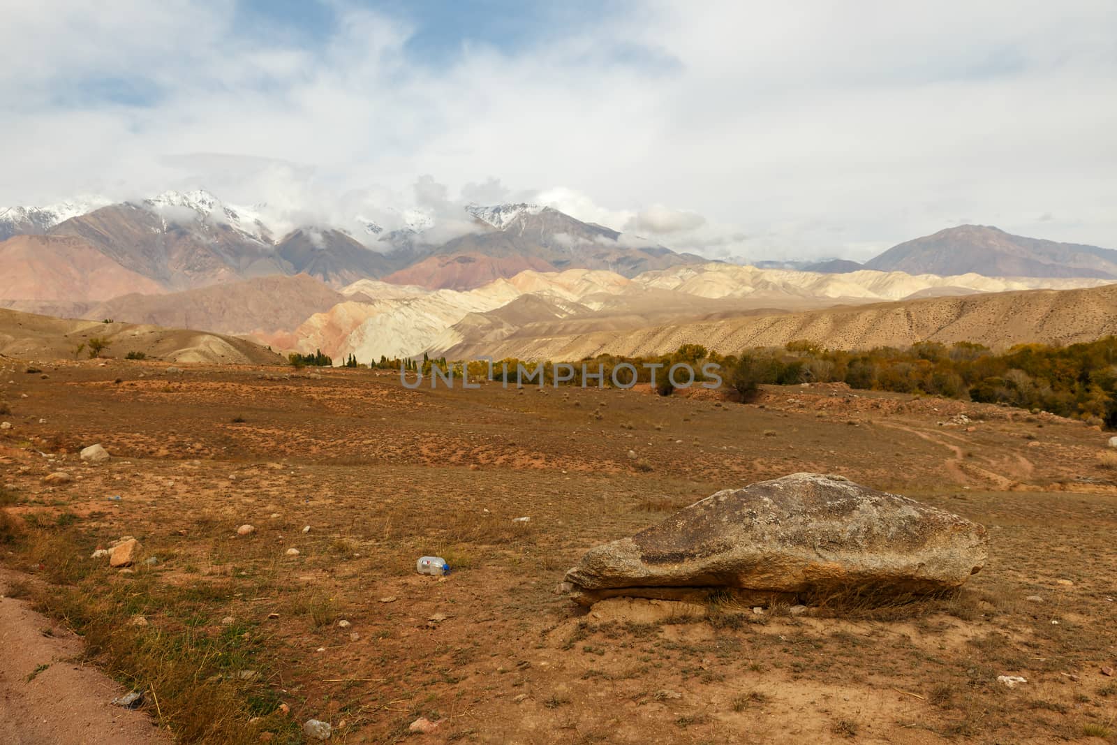 a large stone lies on the ground against the backdrop of beautiful mountains, Jumgal District, Kyrgyzstan mountain landscape