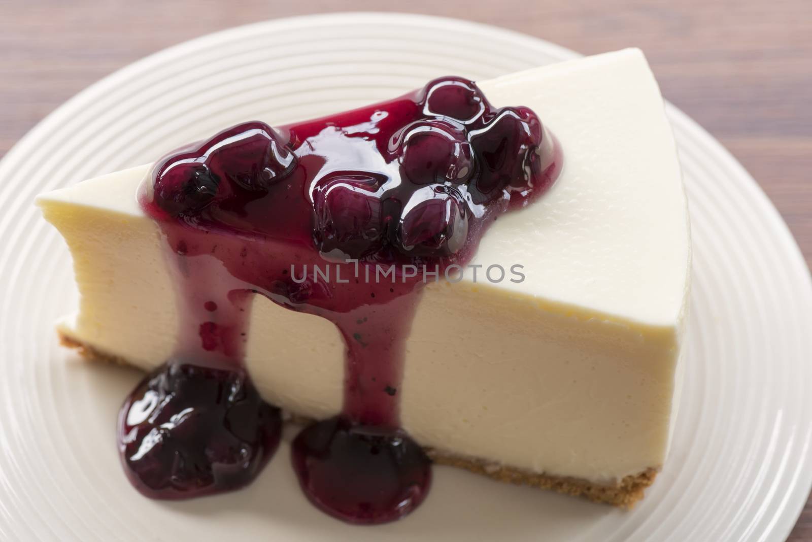 Blueberry cream cheesecake in white plate on wood table